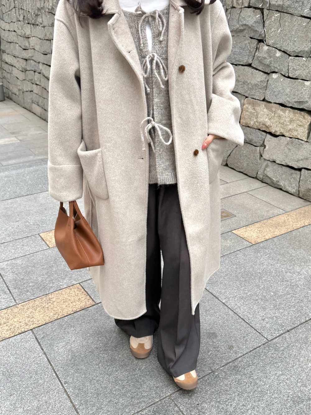 ベージュ系のステンカラーコート、ホワイト系のTシャツ/カットソー、ベージュ系のベストを着用したレディースの冬コーディネートの3枚目の写真