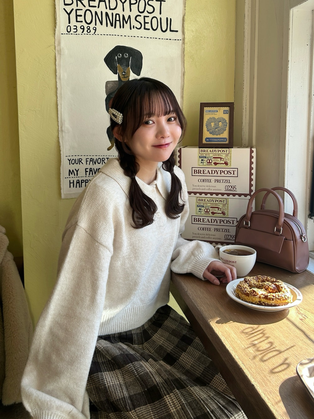 ベージュ系のジャケット/アウター、ホワイト系のニット/セーター、ピンク系のボストンバッグを着用したレディースの冬コーディネートの3枚目の写真