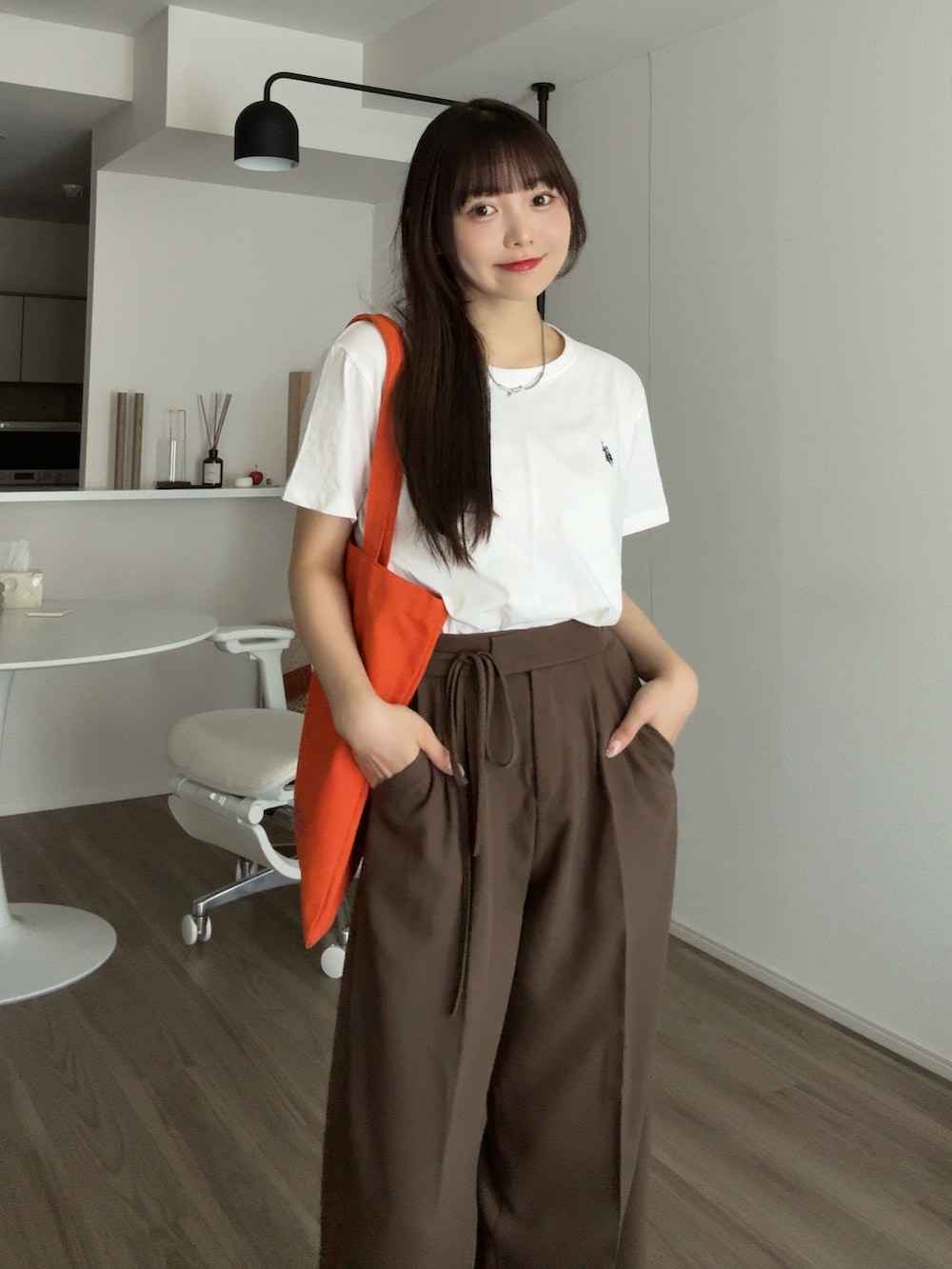 ホワイト系のTシャツ/カットソー、ブラウン系のその他パンツ、オレンジ系のトートバッグを着用したレディースの秋コーディネートの4枚目の写真