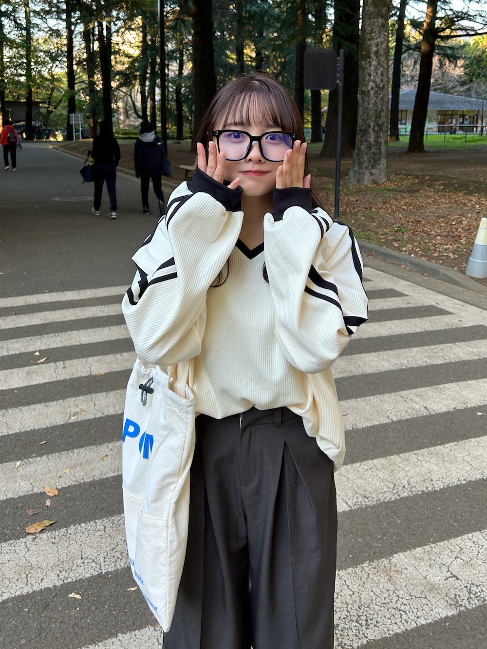 ホワイト系のスウェット、ホワイト系のトートバッグ、グレー系のスラックスを着用したレディースの冬コーディネートの2枚目の写真