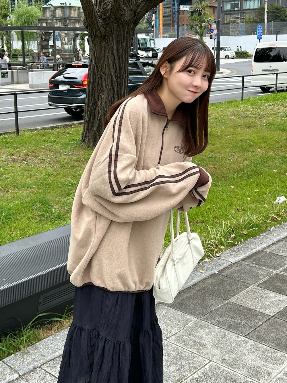 ブラウン系のスウェット、ホワイト系のバッグ、ブラック系のスカートを着用したレディースの秋コーディネートの3枚目の写真