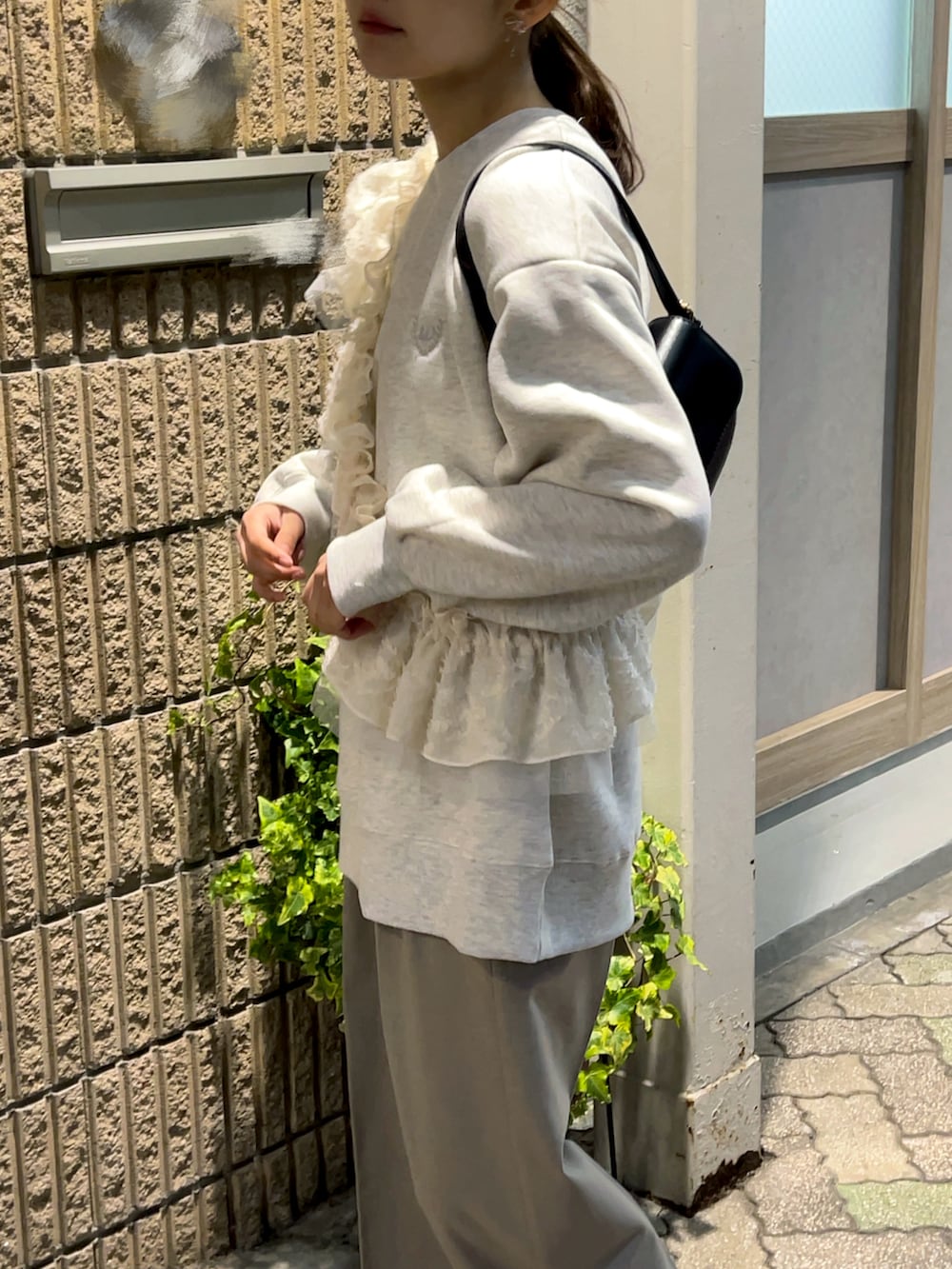 ベージュ系のスウェット、ブラック系のハンドバッグ、グレー系のパンツを着用したレディースの春コーディネートの4枚目の写真