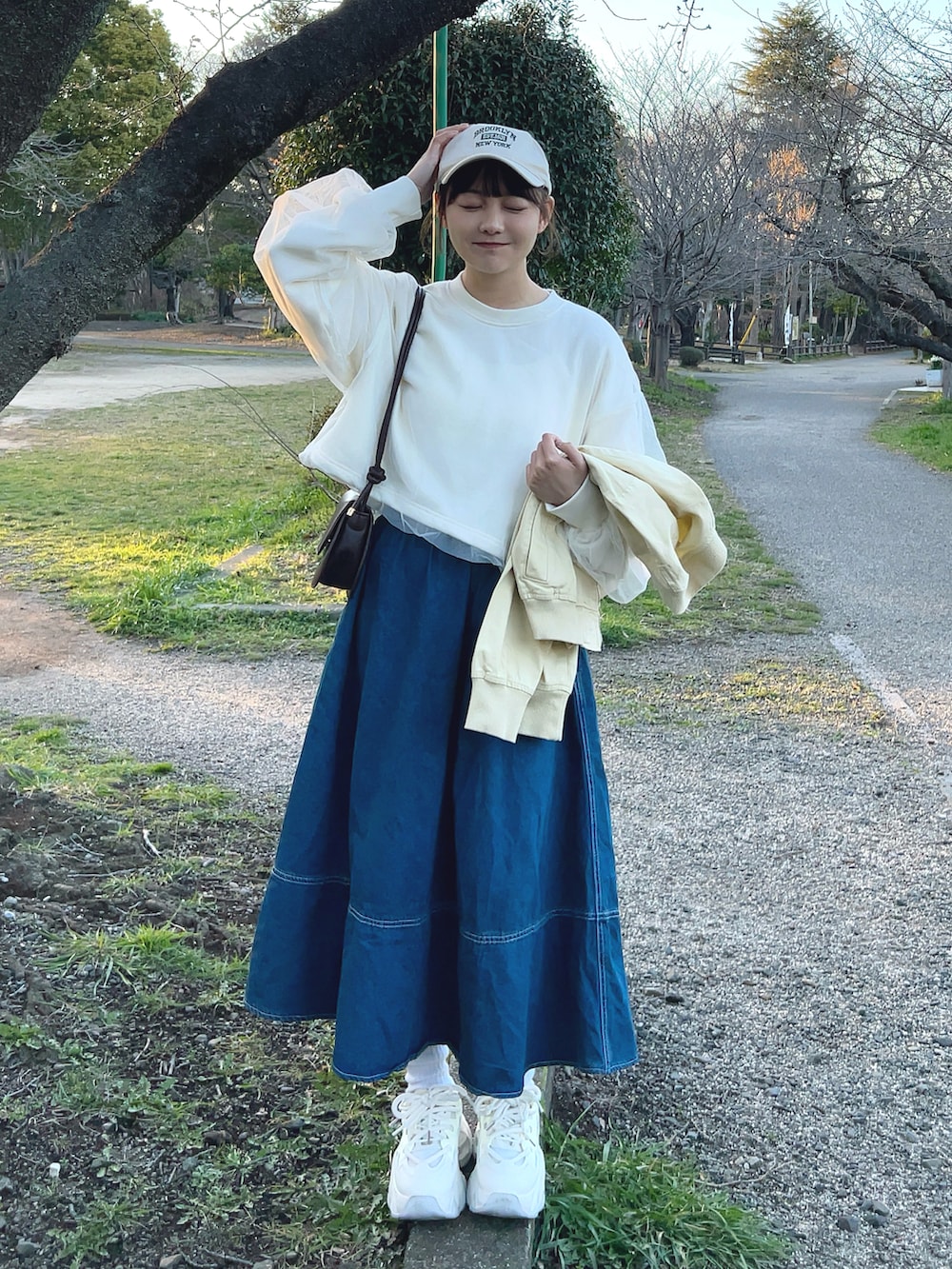 ホワイト系のスウェット、ブルー系のデニムスカート、ホワイト系のスニーカーを着用したレディースの春コーディネートの2枚目の写真