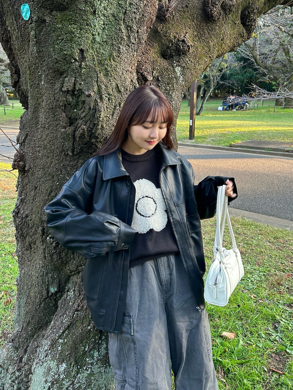 ブラック系のニット/セーター、ブラック系のブルゾン、グレー系のデニムパンツを着用したレディースの秋コーディネートの3枚目の写真