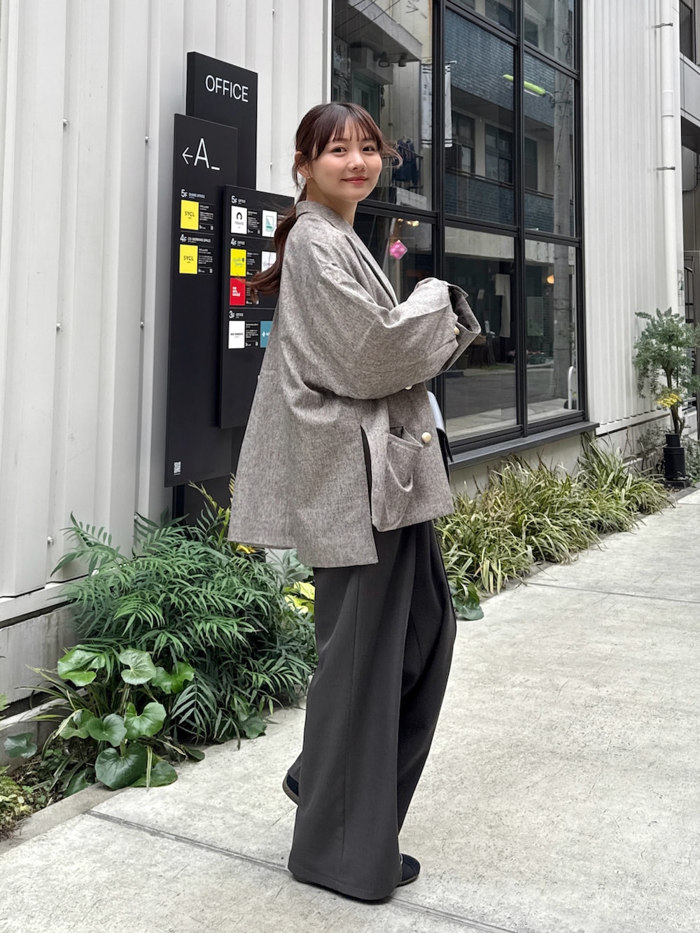 グレー系のスラックス、ホワイト系のスウェット、ベージュ系のテーラードジャケットを着用したレディースの春コーディネートの2枚目の写真