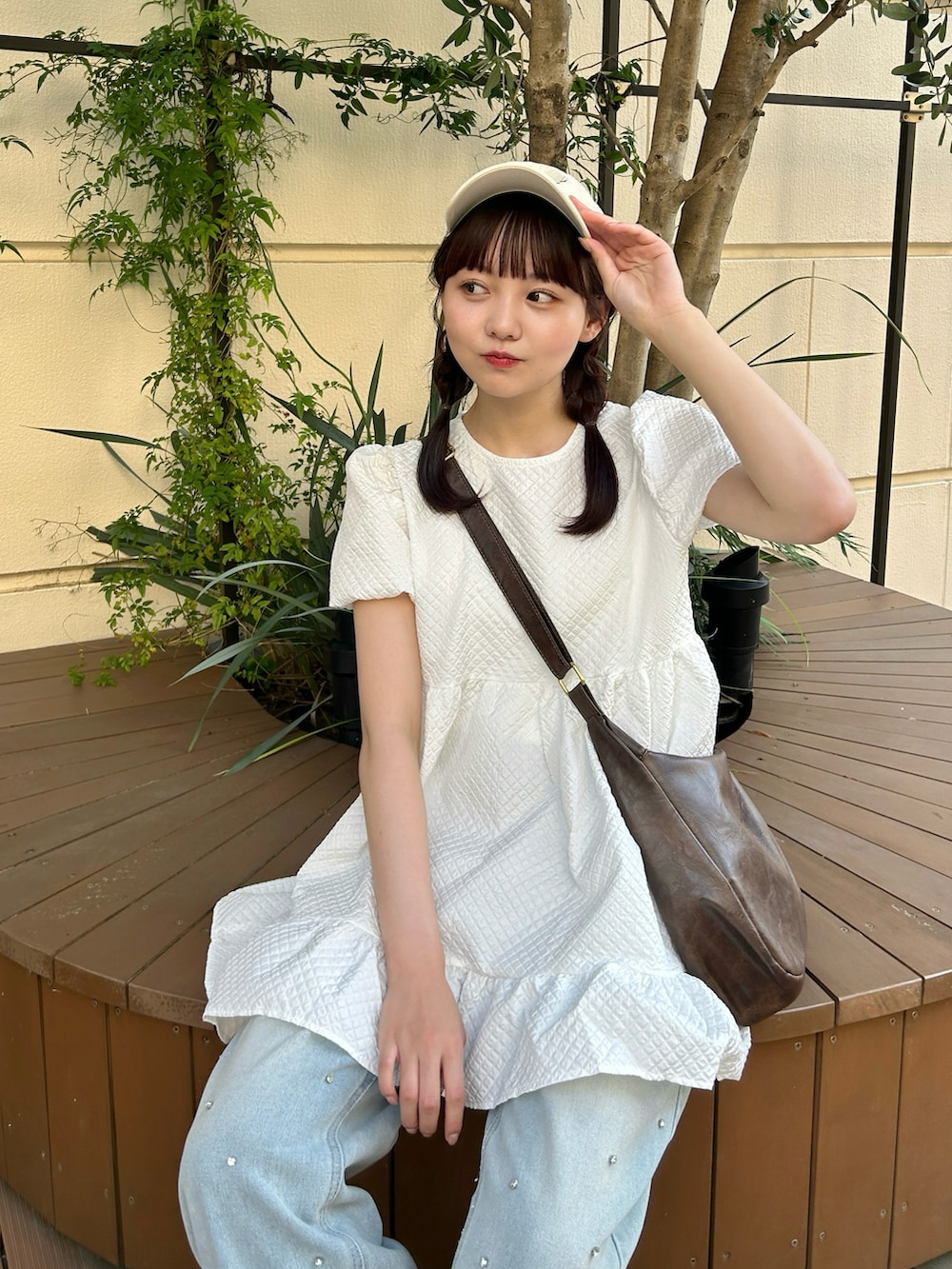 ホワイト系のトップス、ブラウン系のショルダーバッグ、ブルー系のデニムパンツを着用したレディースの夏コーディネートの3枚目の写真