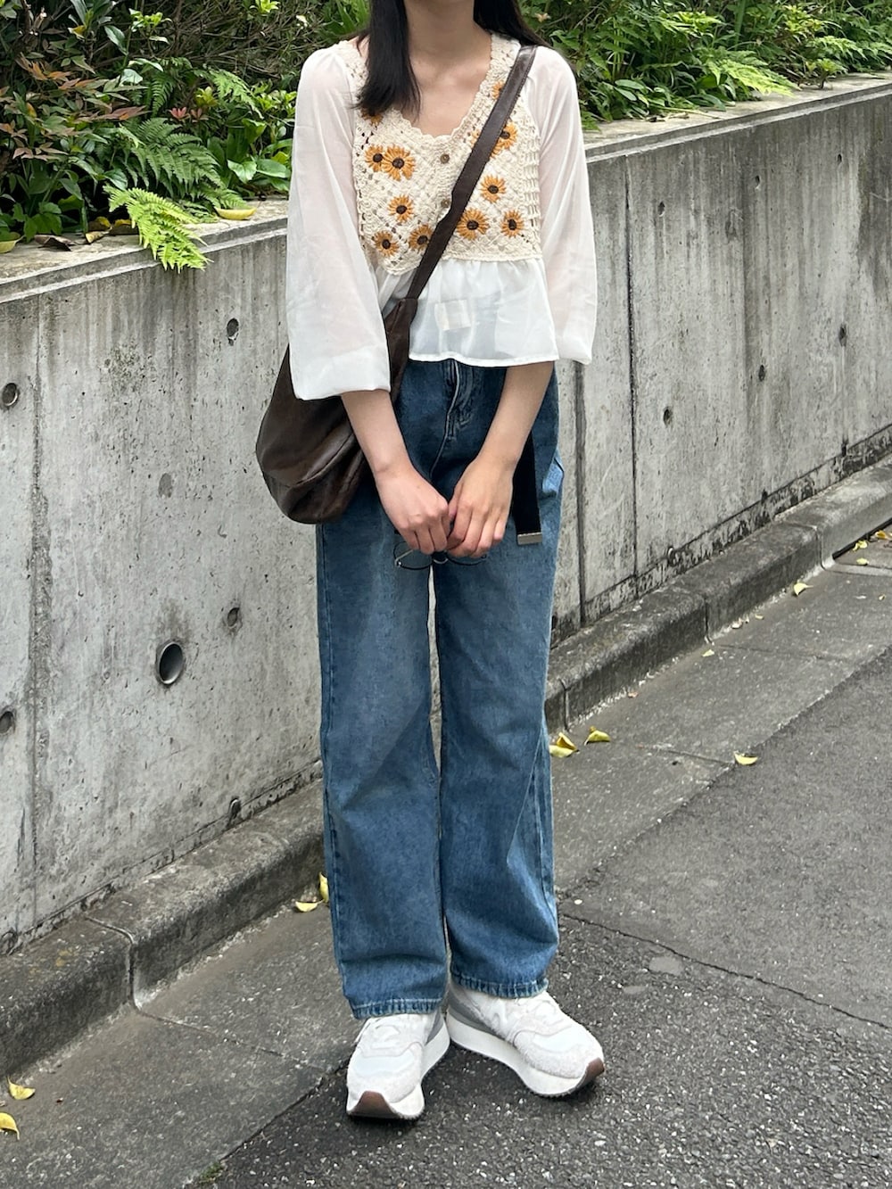 ブルー系のデニムパンツ、ベージュ系のシャツ/ブラウス、ブラウン系のショルダーバッグを着用したレディースの春コーディネートの2枚目の写真