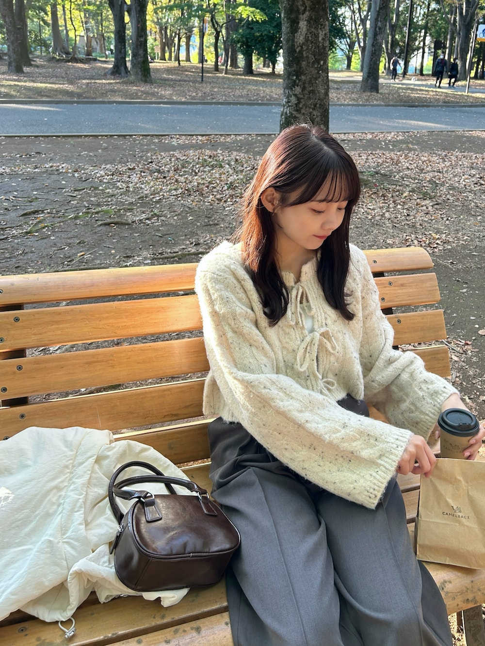 ブラウン系のハンドバッグ、ブラック系のバレエシューズ、グレー系のスラックスを着用したレディースの秋コーディネートの2枚目の写真