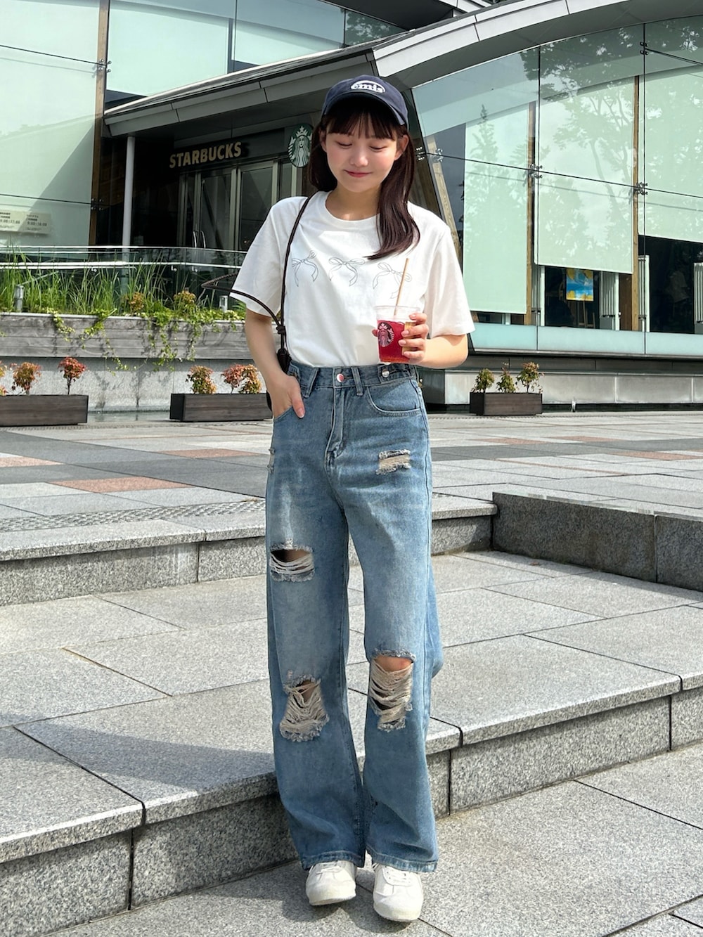 ブルー系のデニムパンツ、ブラウン系のバッグ、ホワイト系のTシャツ/カットソーを着用したレディースの秋コーディネートの2枚目の写真