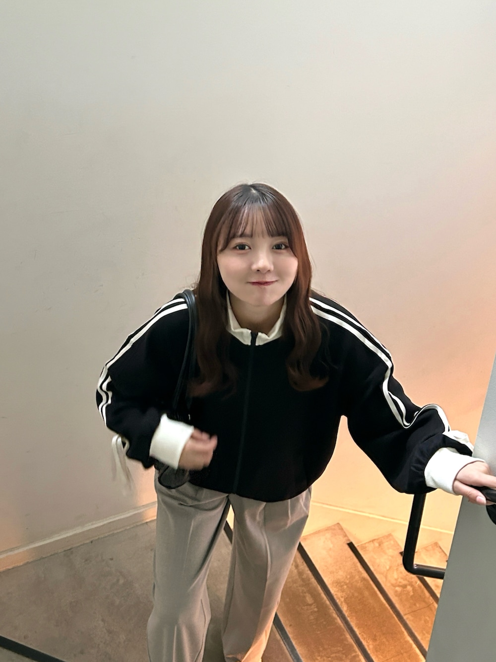 ブラック系のジャージ、ブラック系のバッグ、ベージュ系のパンツを着用したレディースの秋コーディネートの3枚目の写真