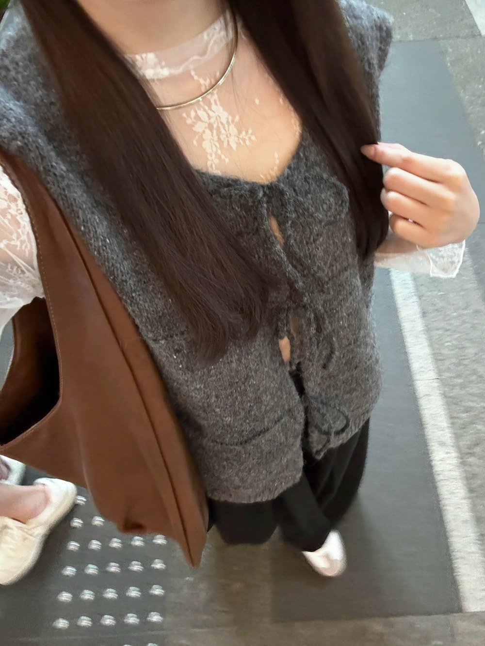 グレー系のベスト、ブラック系のその他パンツ、ホワイト系のスニーカーを着用したレディースの秋コーディネートの5枚目の写真