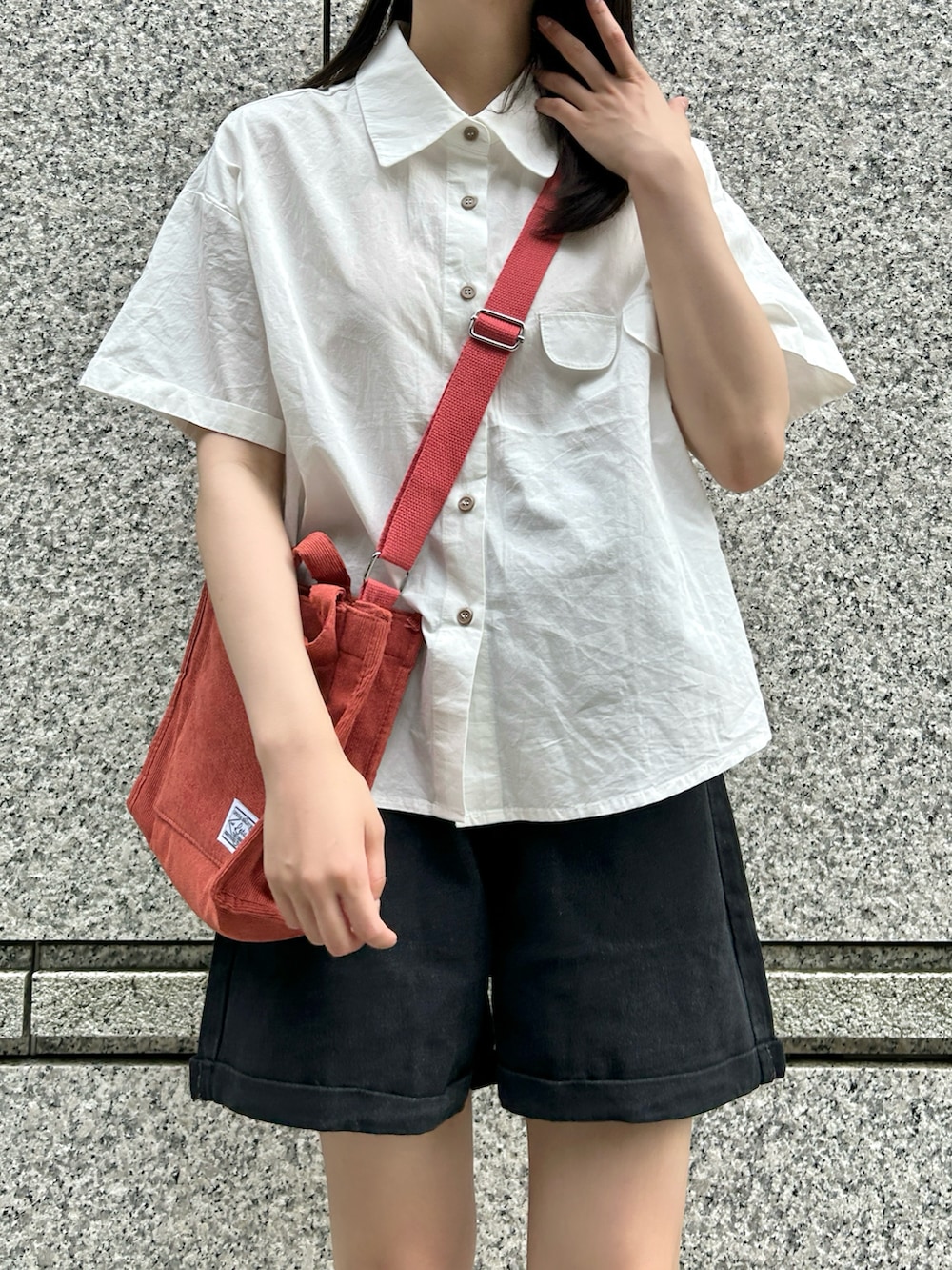 レッド系のショルダーバッグ、ベージュ系のサンダル、ホワイト系のシャツ/ブラウスを着用したレディースの夏コーディネートの3枚目の写真