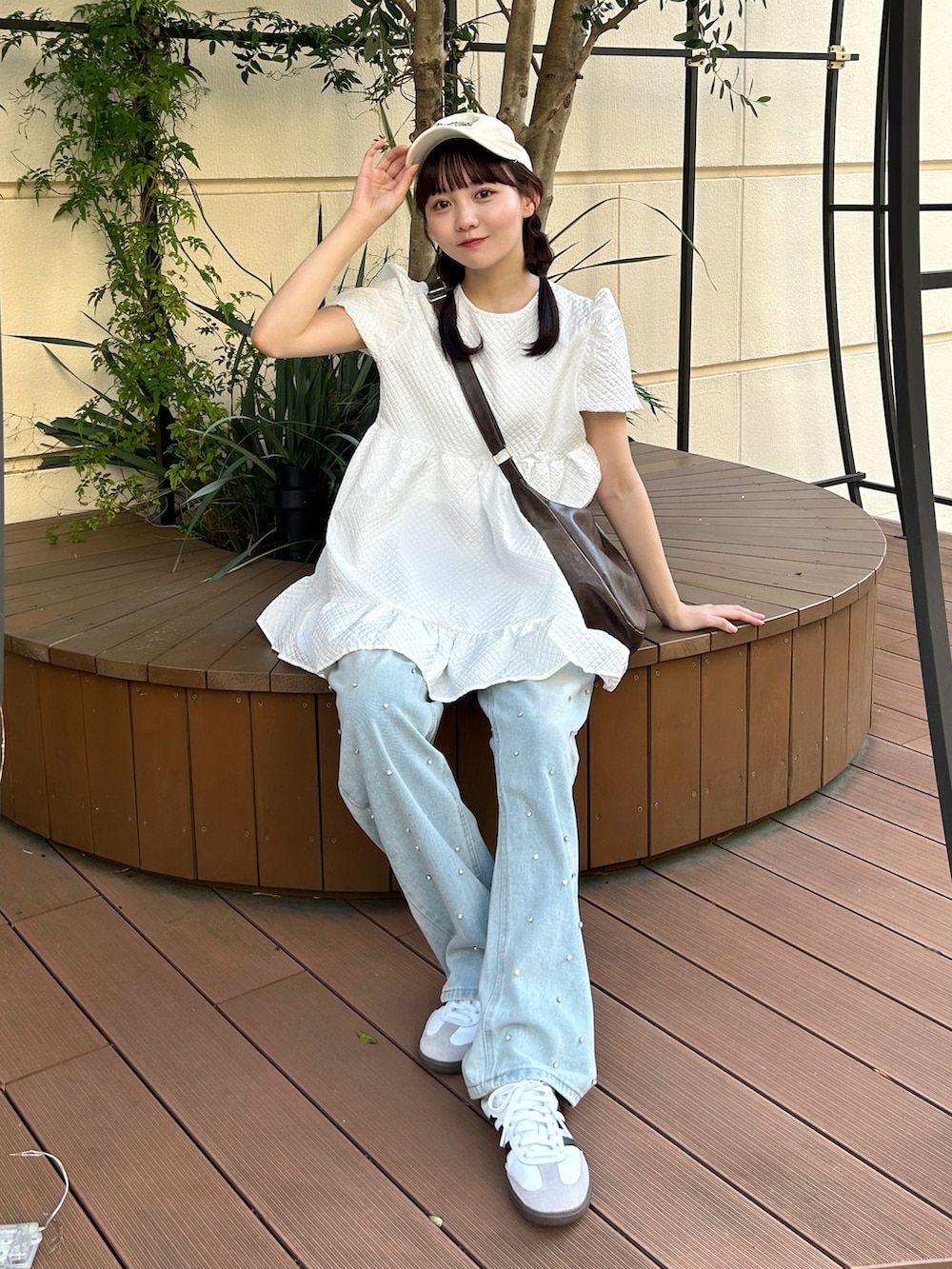 ホワイト系のトップス、ブラウン系のショルダーバッグ、ブルー系のデニムパンツを着用したレディースの夏コーディネートの2枚目の写真