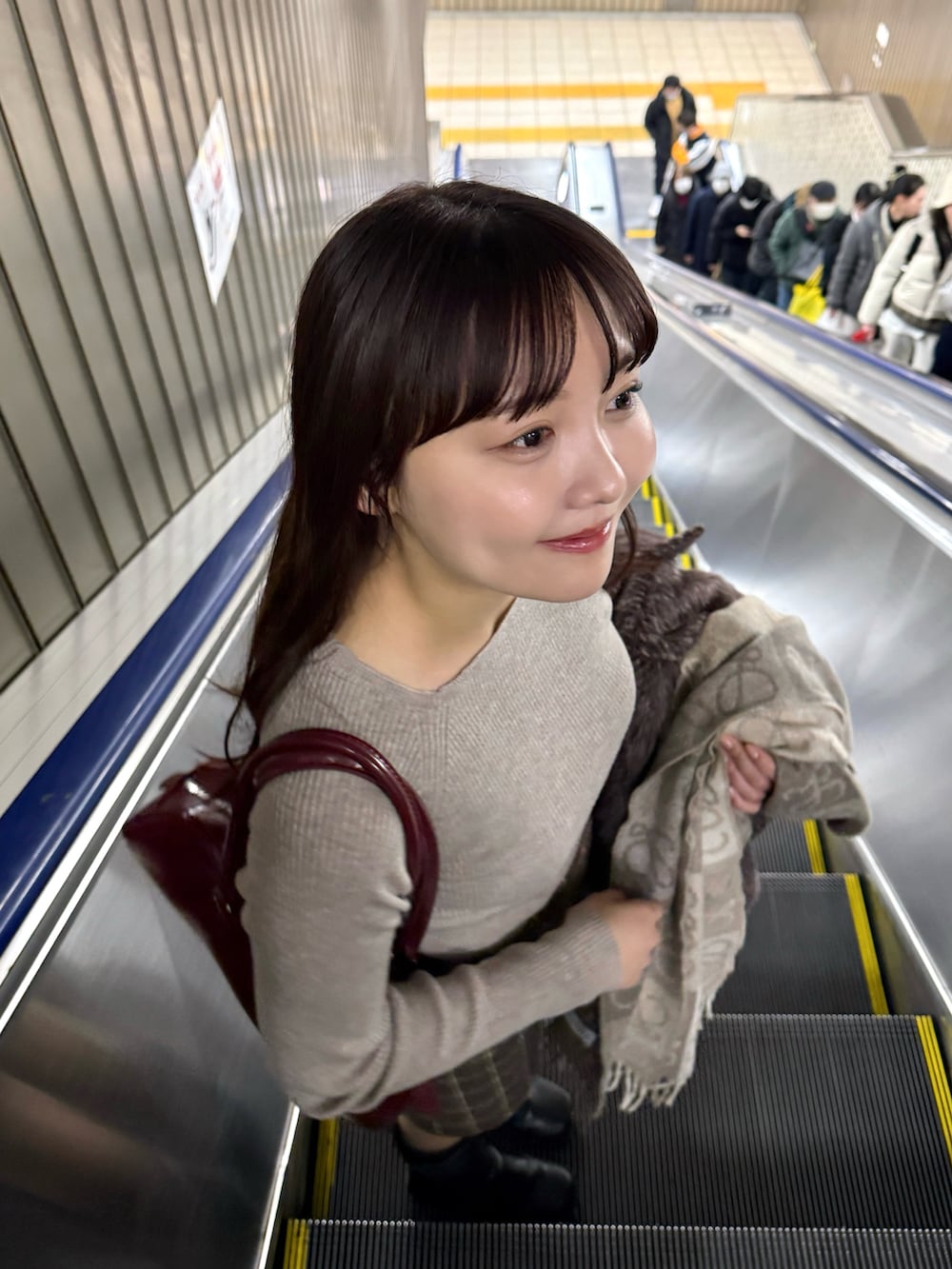 ブラウン系のスカート、レッド系のボストンバッグ、ブラウン系のピーコートを着用したレディースの冬コーディネートの4枚目の写真