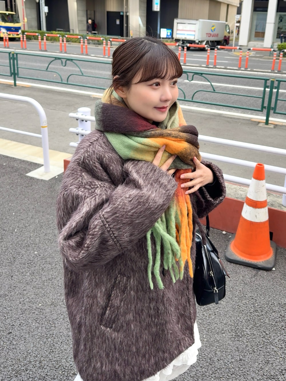 ブラウン系のピーコート、ホワイト系のワンピース、ブラック系のショルダーバッグを着用したレディースの冬コーディネートの3枚目の写真