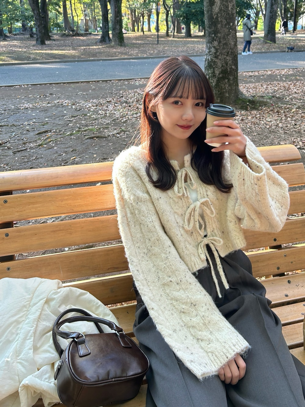 ブラウン系のハンドバッグ、ブラック系のバレエシューズ、グレー系のスラックスを着用したレディースの秋コーディネートの5枚目の写真