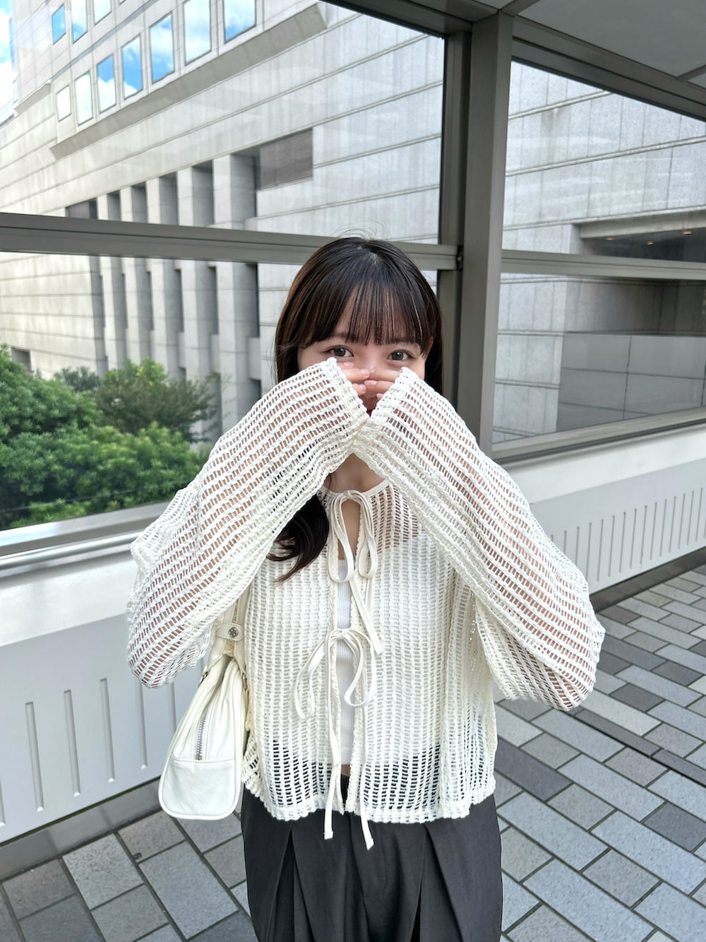 ベージュ系のカーディガン/ボレロ、ホワイト系のバッグ、グレー系のスラックスを着用したレディースの春コーディネートの2枚目の写真