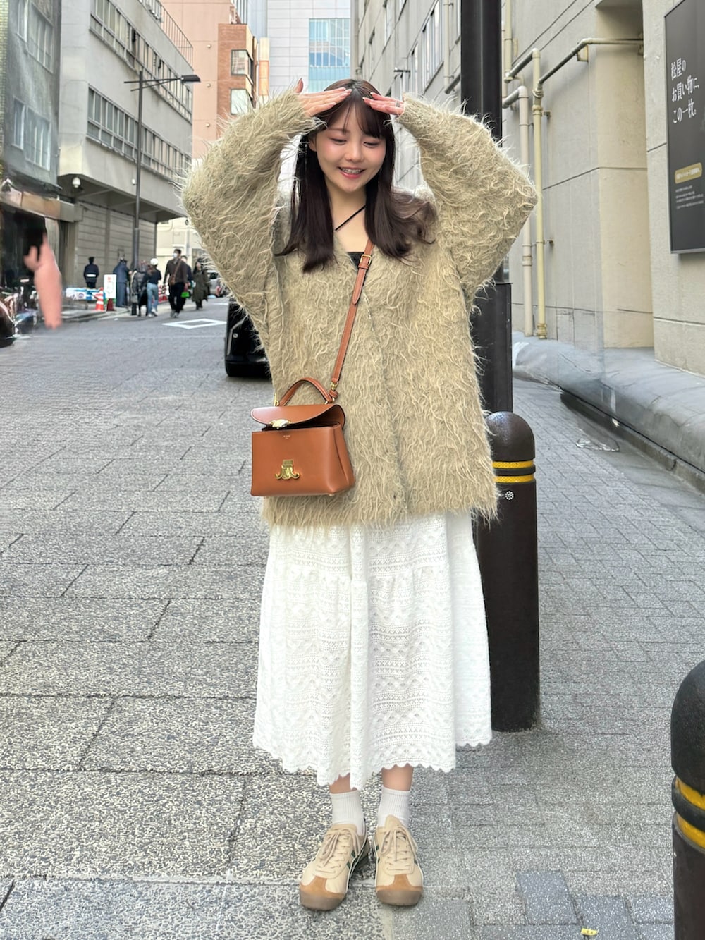 ベージュ系のタンクトップ、グリーン系のカーディガン/ボレロ、ホワイト系のスカートを着用したレディースの春コーディネートの4枚目の写真