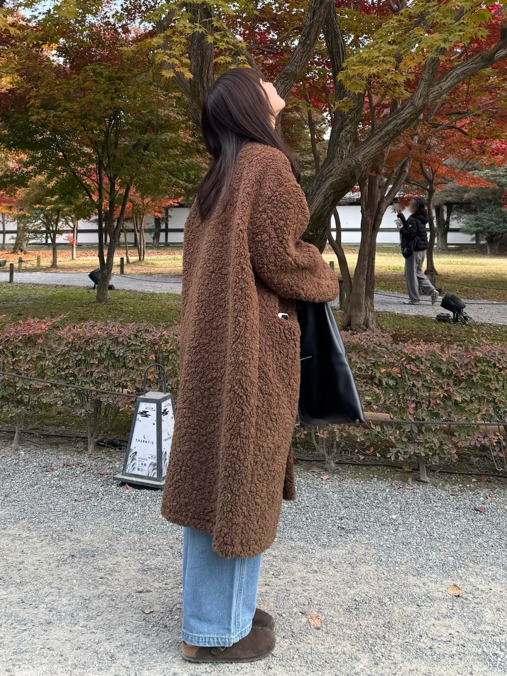 ブルー系のデニムパンツ、ブラック系のハンドバッグ、ブラウン系のサンダルを着用したレディースの冬コーディネートの2枚目の写真