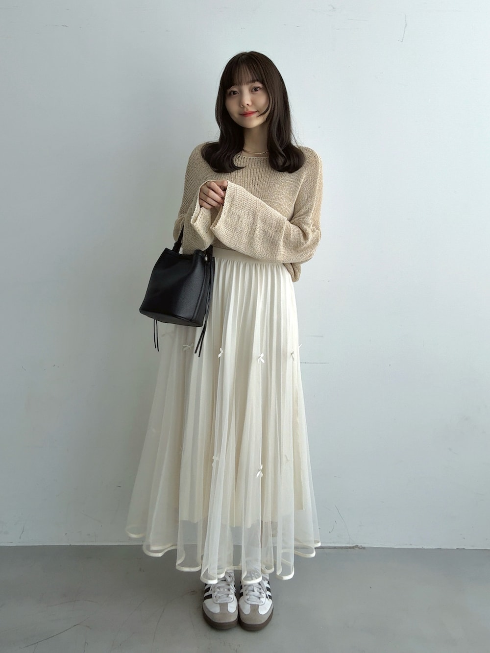 ベージュ系のニット/セーター、ホワイト系のスカート、ブラック系のハンドバッグを着用したレディースの秋コーディネートの2枚目の写真