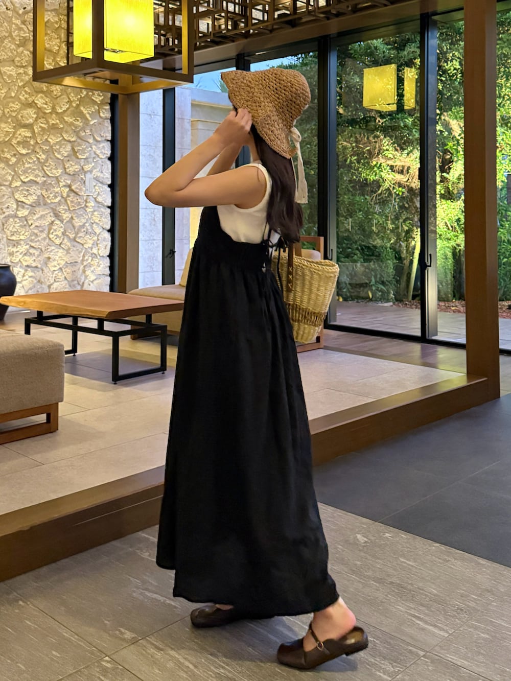 ブラウン系のパンプス、ブラック系のワンピース、ホワイト系のかごバッグを着用したレディースの夏コーディネートの2枚目の写真