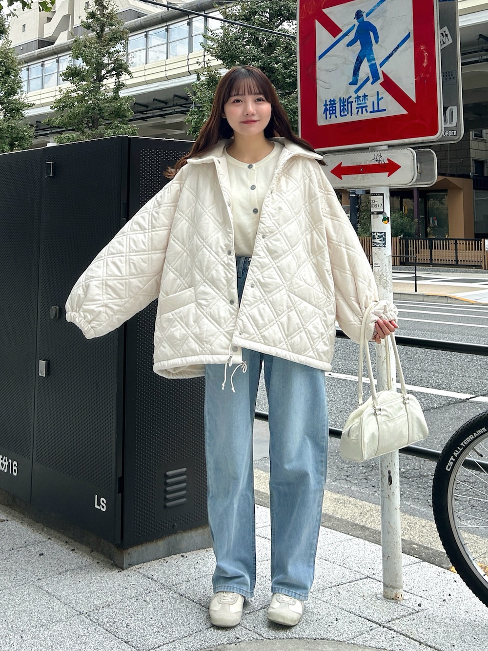 ブルー系のトップス、ブルー系のデニムパンツ、ベージュ系のスニーカーを着用したレディースの秋コーディネートの4枚目の写真