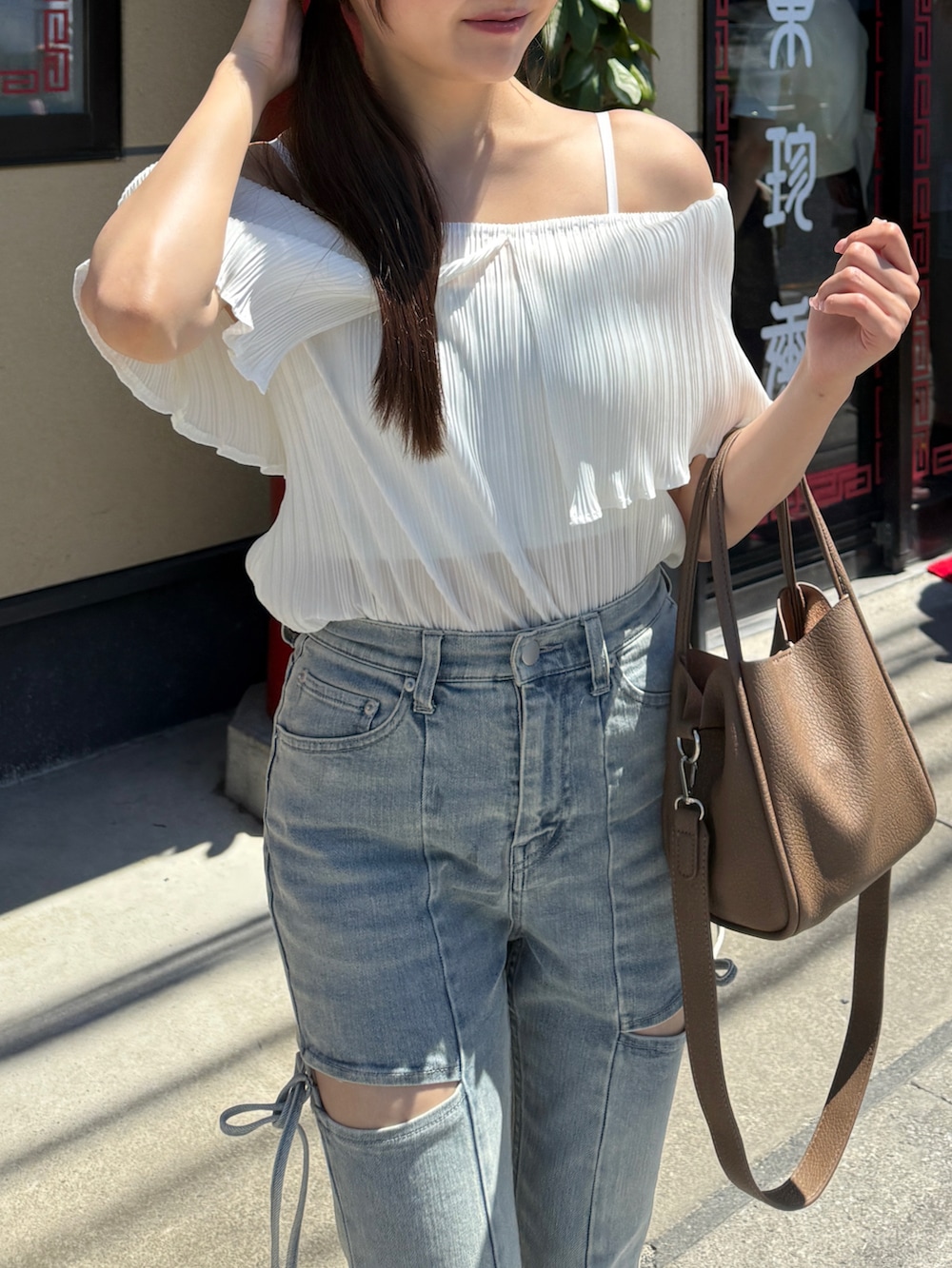 ブルー系のデニムパンツ、ホワイト系のサンダル、ホワイト系のシャツ/ブラウスを着用したレディースの夏コーディネートの2枚目の写真