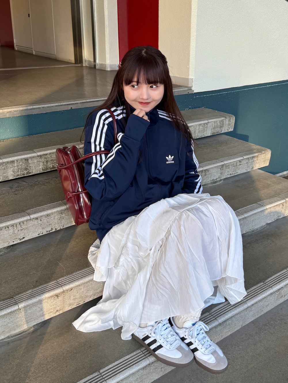 ブルー系のジャージ、レッド系のボストンバッグ、ホワイト系のスカートを着用したレディースの冬コーディネートの4枚目の写真