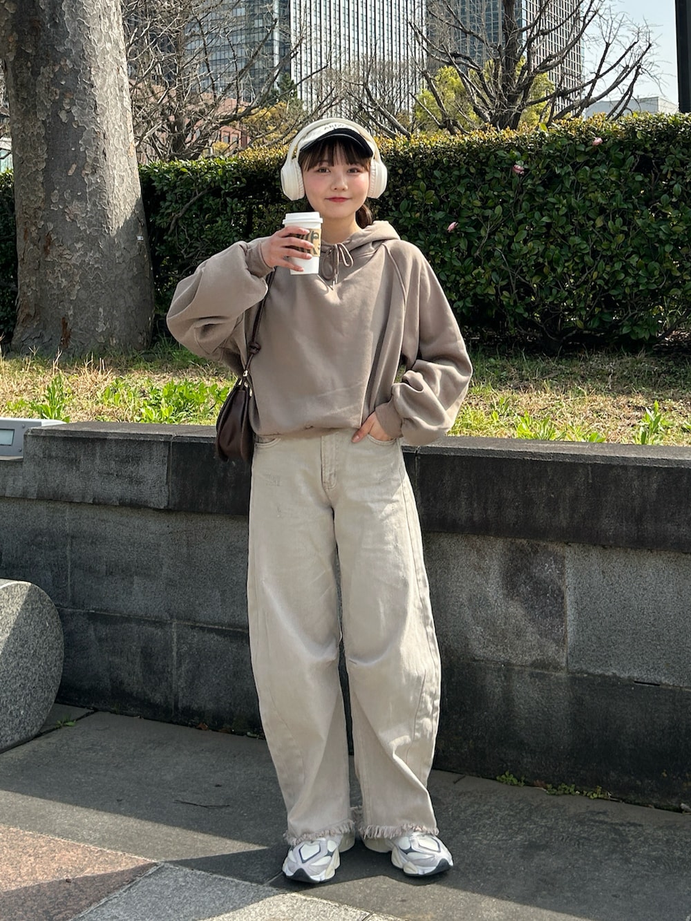 ベージュ系のデニムパンツ、ベージュ系のスニーカー、ブラウン系のハンドバッグを着用したレディースの春コーディネートの4枚目の写真