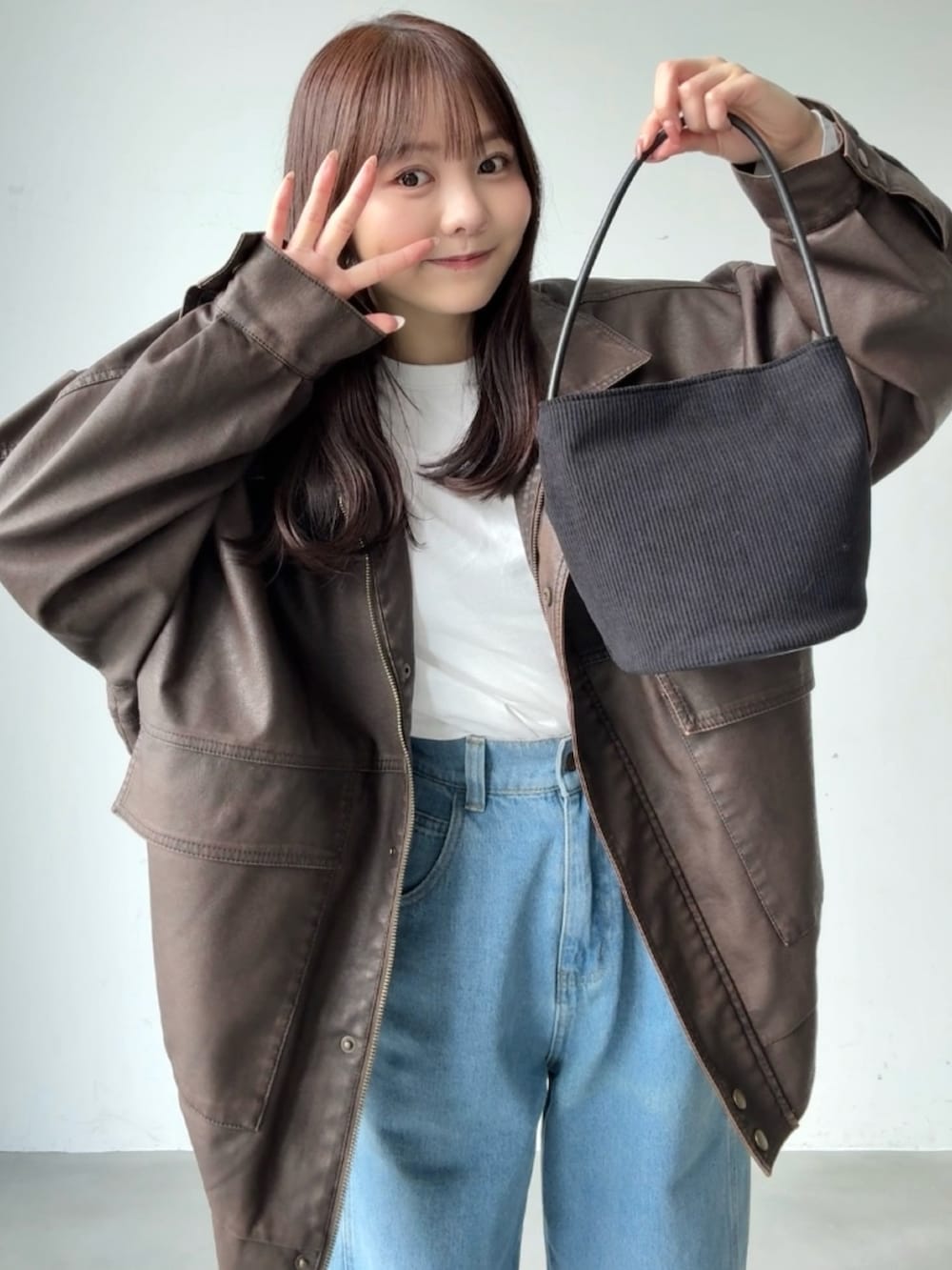 ブラック系のショルダーバッグ、ブラウン系のブルゾン、ホワイト系のTシャツ/カットソーを着用したレディースの春コーディネートの3枚目の写真