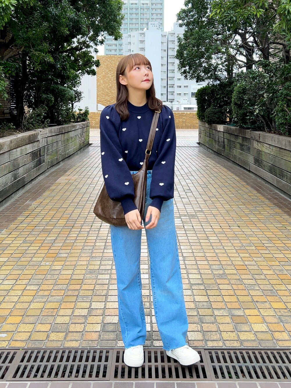 ブルー系のニット/セーター、ブラウン系のショルダーバッグ、ブルー系のデニムパンツを着用したレディースの春コーディネートの3枚目の写真