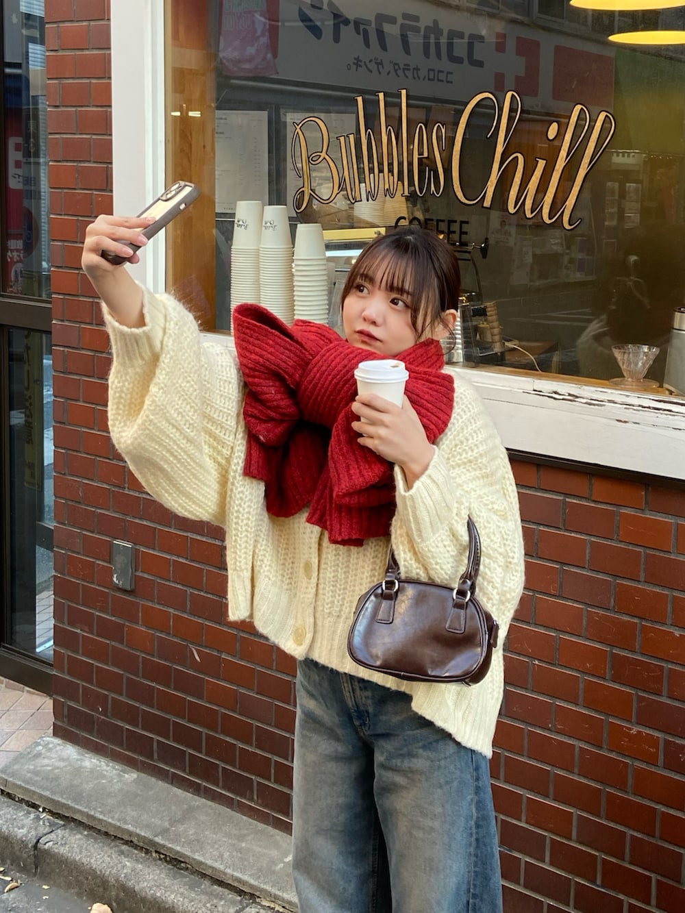 ホワイト系のカーディガン/ボレロ、ホワイト系のブルゾン、ブラウン系のハンドバッグを着用したレディースの冬コーディネートの3枚目の写真