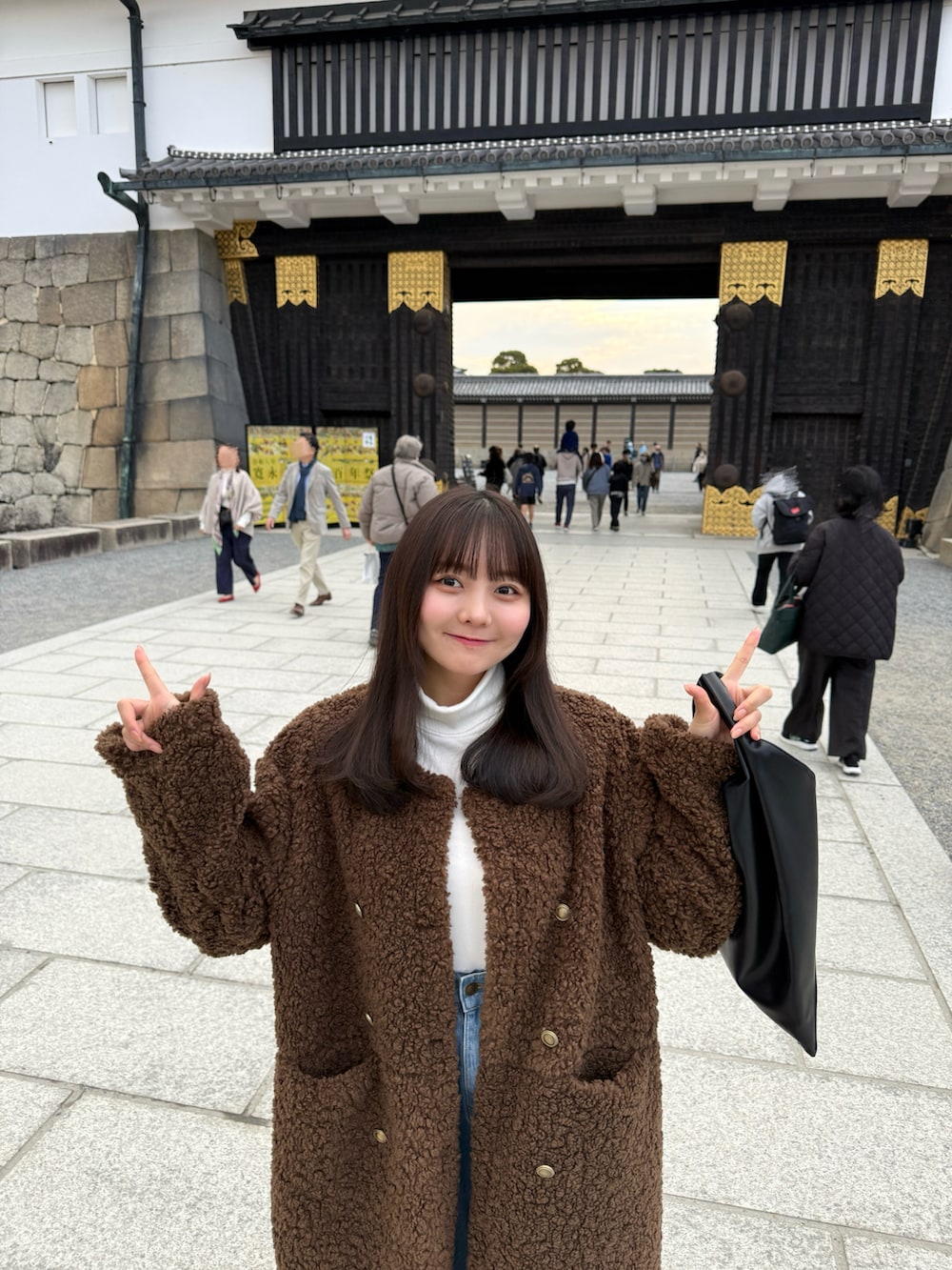 ブルー系のデニムパンツ、ブラック系のハンドバッグ、ブラウン系のサンダルを着用したレディースの冬コーディネートの3枚目の写真