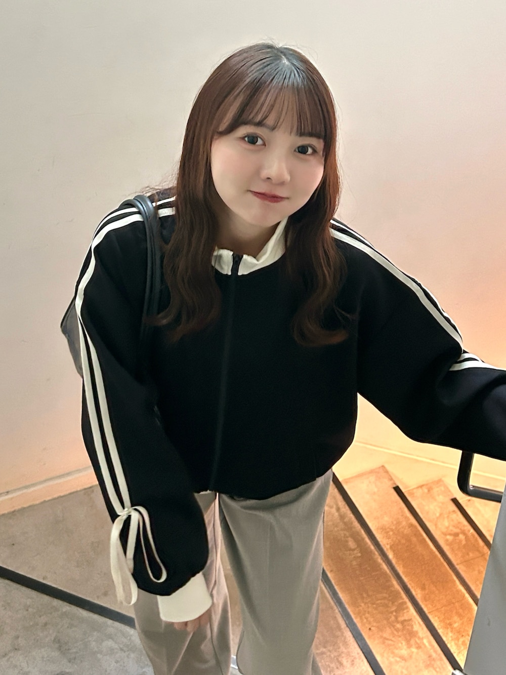 ブラック系のジャージ、ブラック系のバッグ、ベージュ系のパンツを着用したレディースの秋コーディネートの2枚目の写真