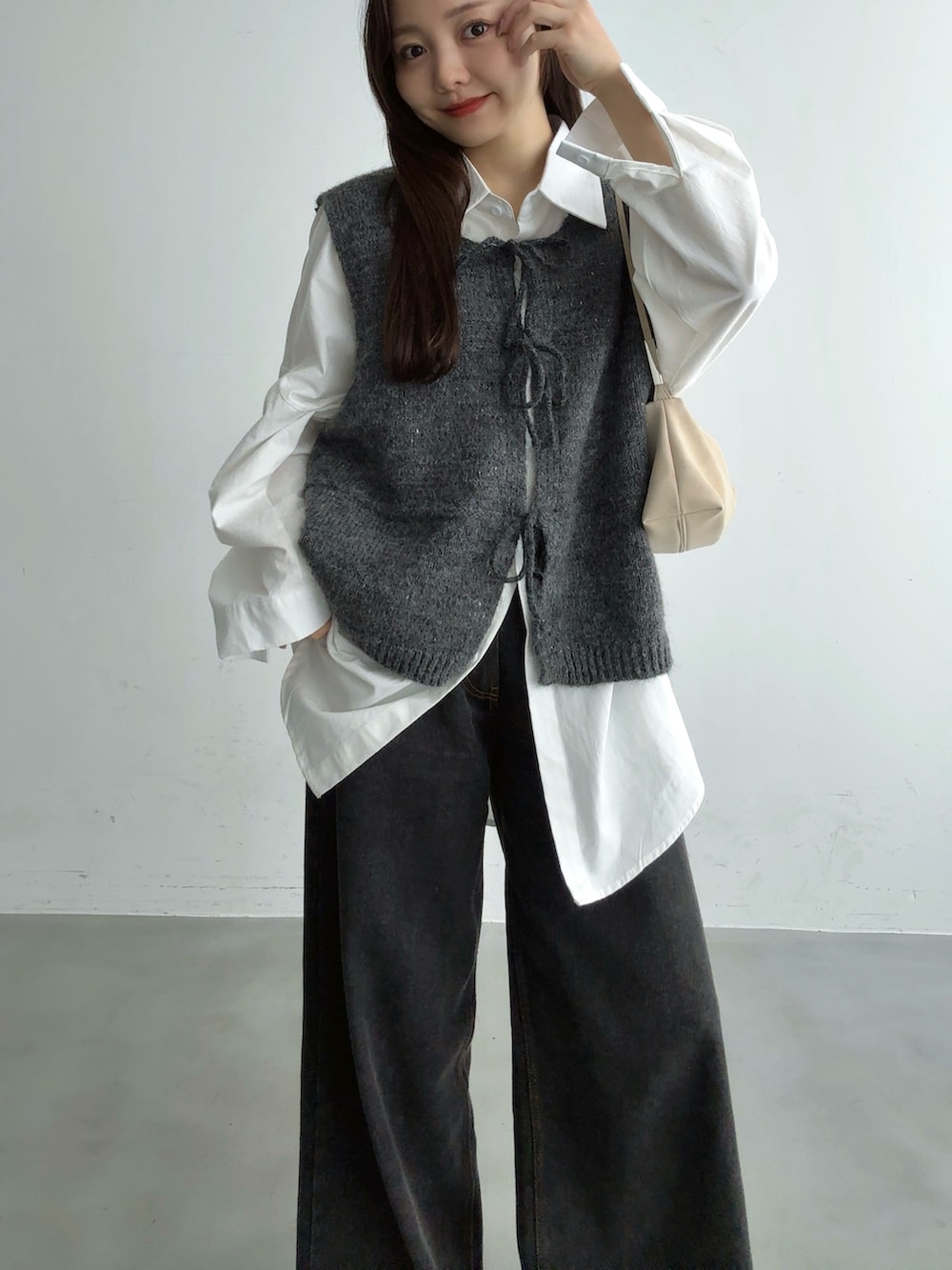 グレー系のベスト、ブラック系のその他パンツ、ホワイト系のショルダーバッグを着用したレディースの秋コーディネートの5枚目の写真