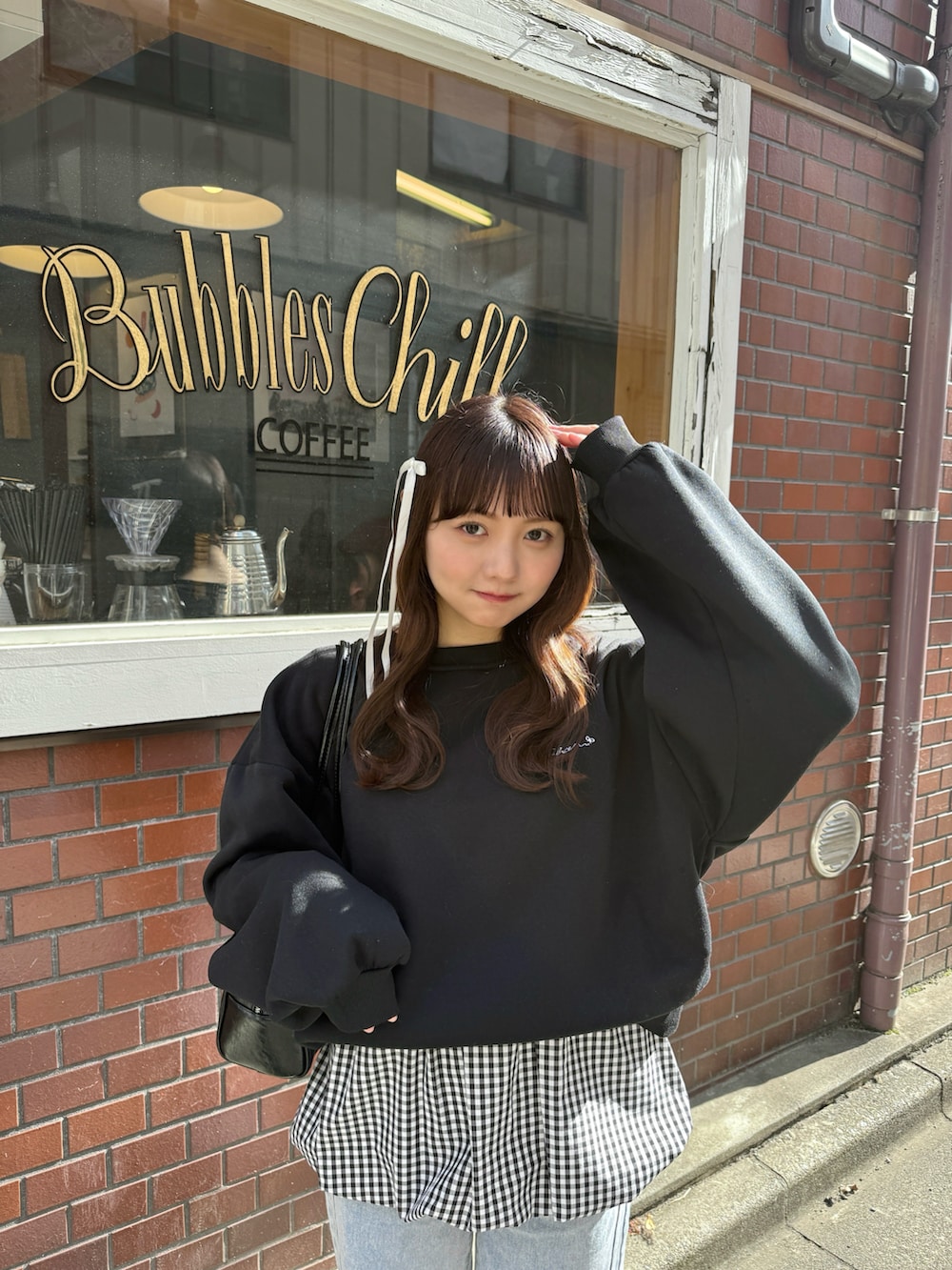 ブラック系のスウェット、ブラック系のショルダーバッグ、ホワイト系のトップスを着用したレディースの春コーディネートの3枚目の写真