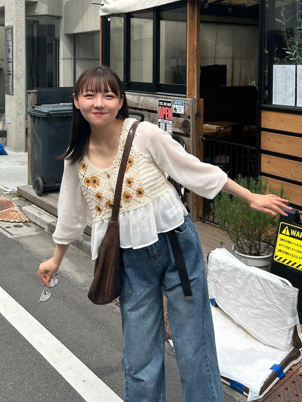 ブルー系のデニムパンツ、ベージュ系のシャツ/ブラウス、ブラウン系のショルダーバッグを着用したレディースの春コーディネートの5枚目の写真