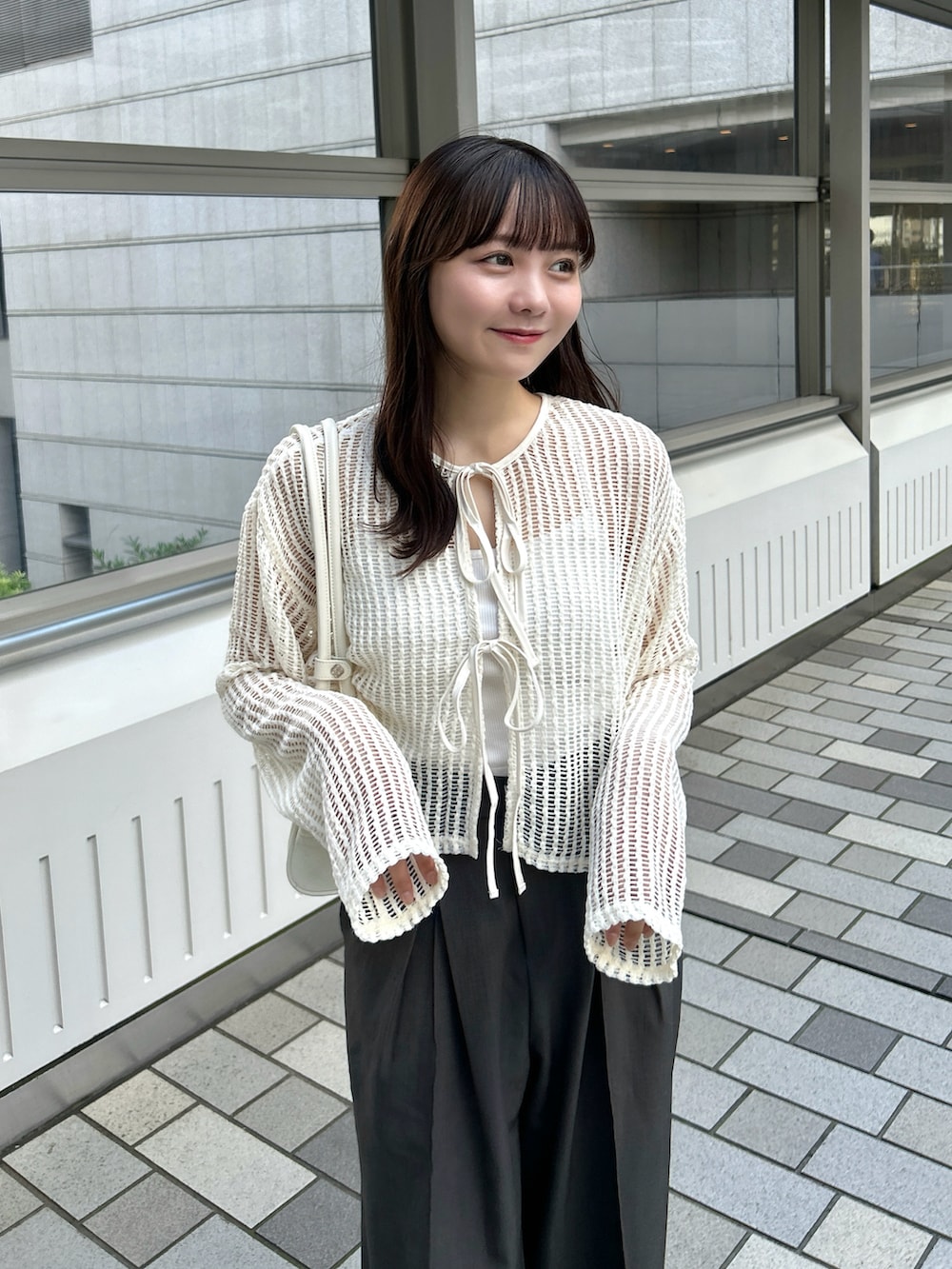 ベージュ系のカーディガン/ボレロ、グレー系のスラックス、ホワイト系のバッグを着用したレディースの秋コーディネートの3枚目の写真