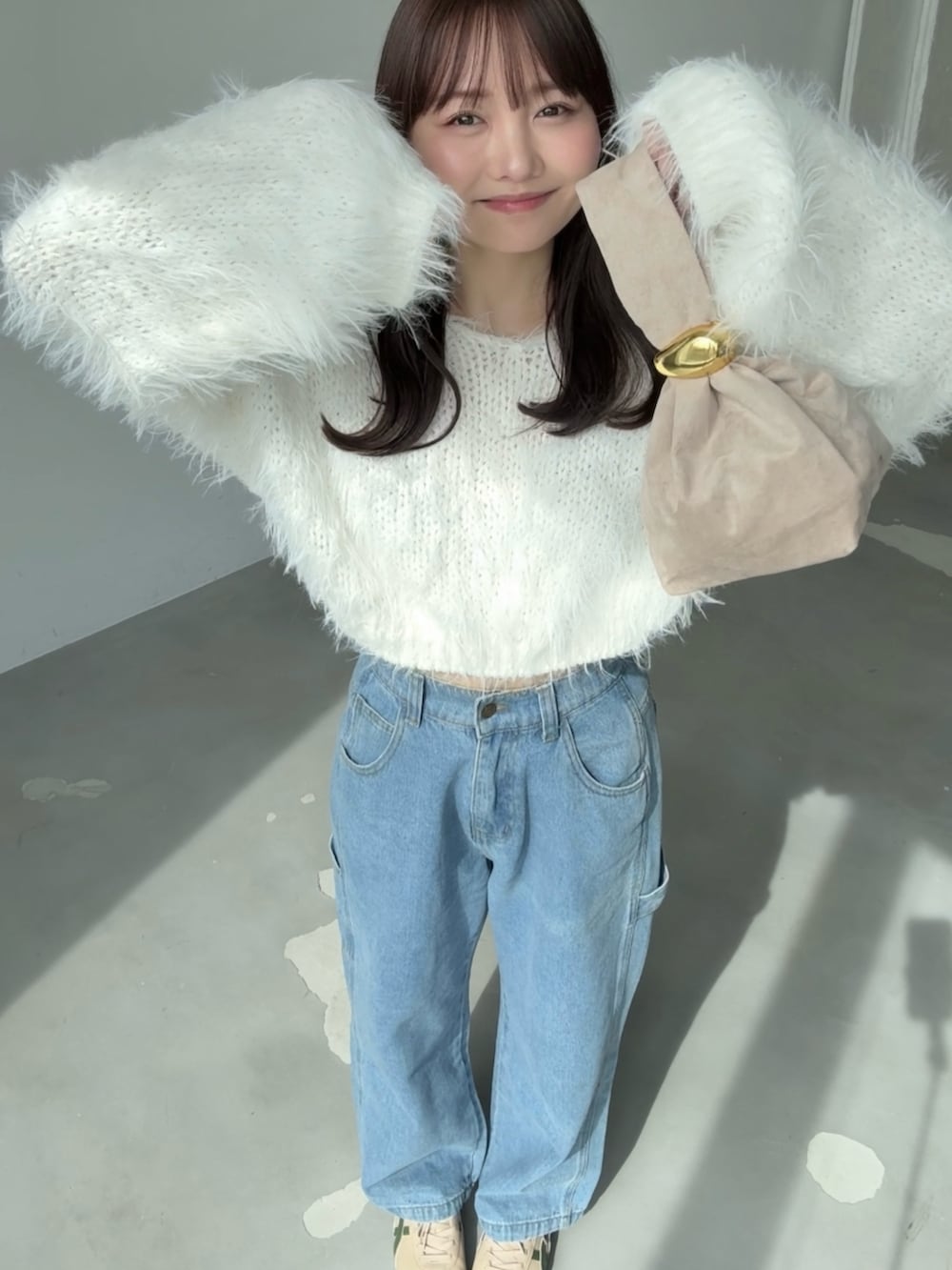 ホワイト系のニット/セーター、ブラウン系のブルゾン、ブルー系のデニムパンツを着用したレディースの春コーディネートの3枚目の写真