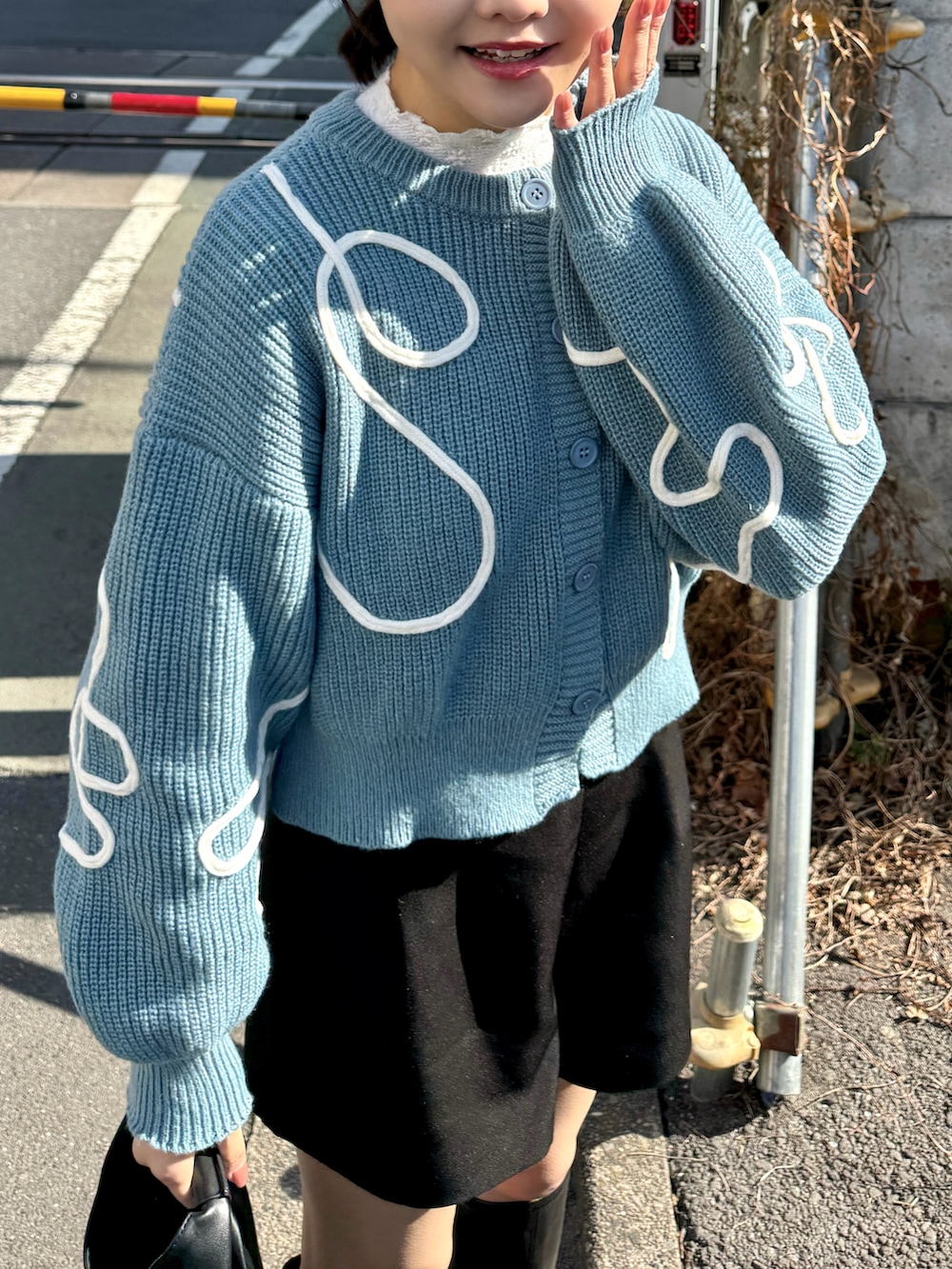 ブルー系のカーディガン/ボレロ、ホワイト系のTシャツ/カットソー、ブラック系のハンドバッグを着用したレディースの冬コーディネートの3枚目の写真