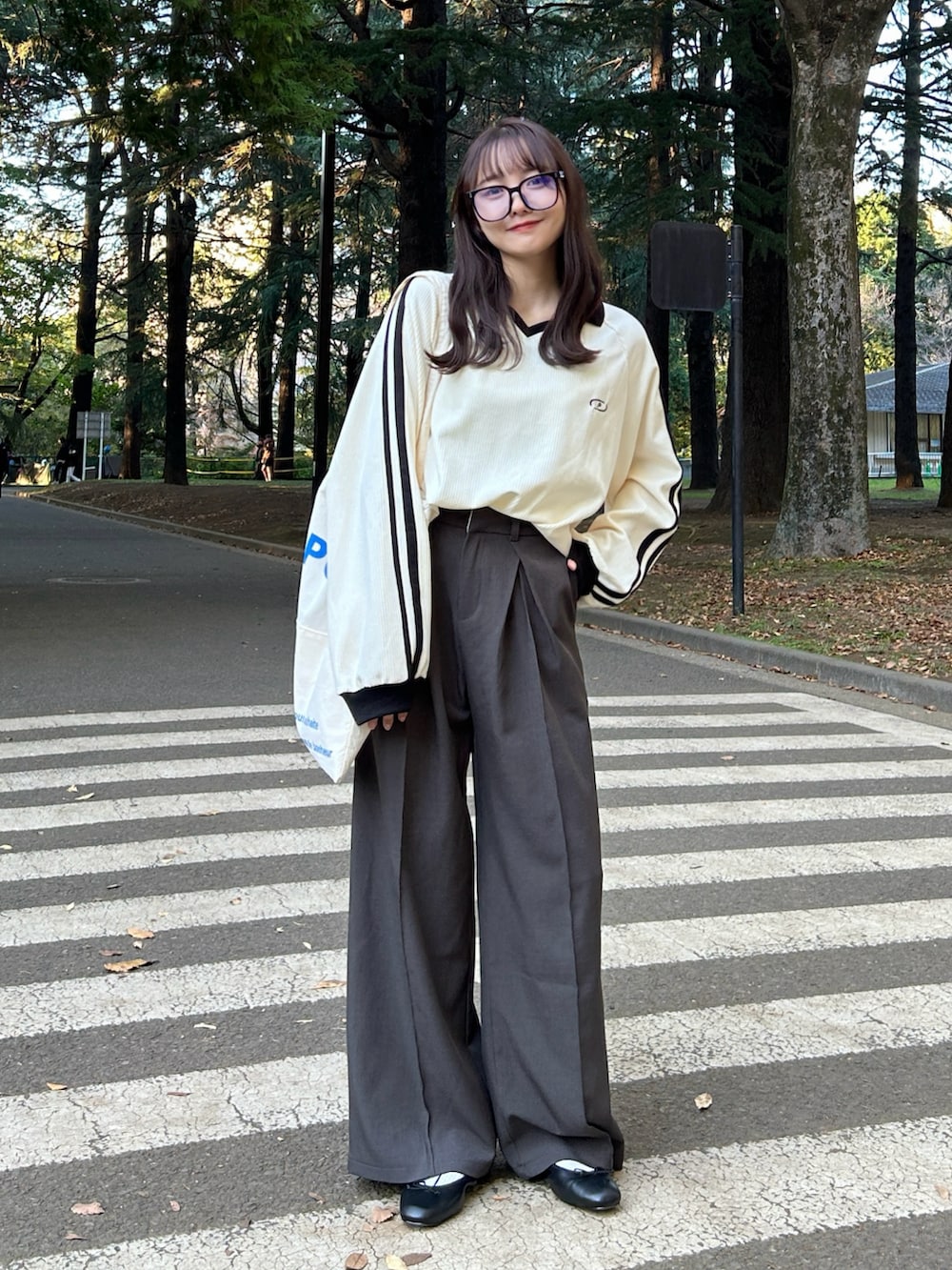 ホワイト系のスウェット、ホワイト系のトートバッグ、グレー系のスラックスを着用したレディースの冬コーディネートの4枚目の写真