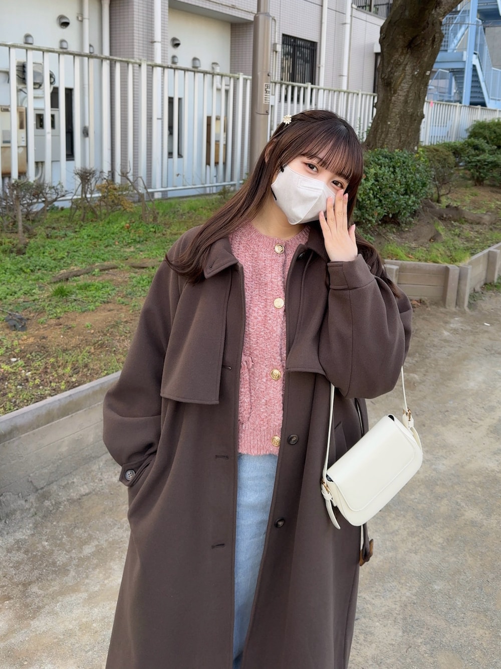 レッド系のカーディガン/ボレロ、ブラウン系のステンカラーコート、ブルー系のデニムパンツを着用したレディースの冬コーディネートの2枚目の写真