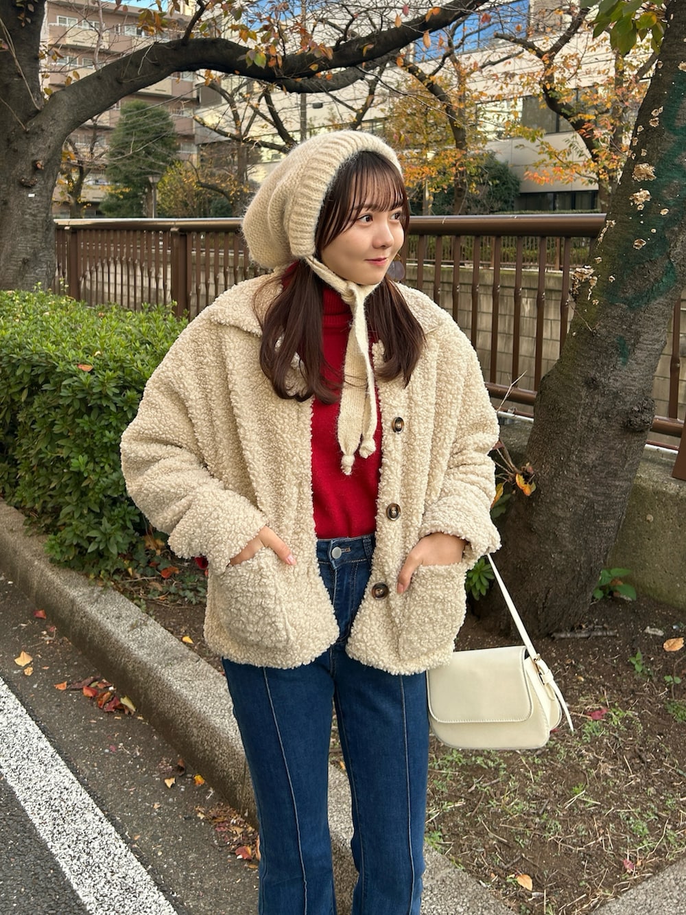 レッド系のニット/セーター、ホワイト系のブルゾン、ブルー系のデニムパンツを着用したレディースの冬コーディネートの4枚目の写真