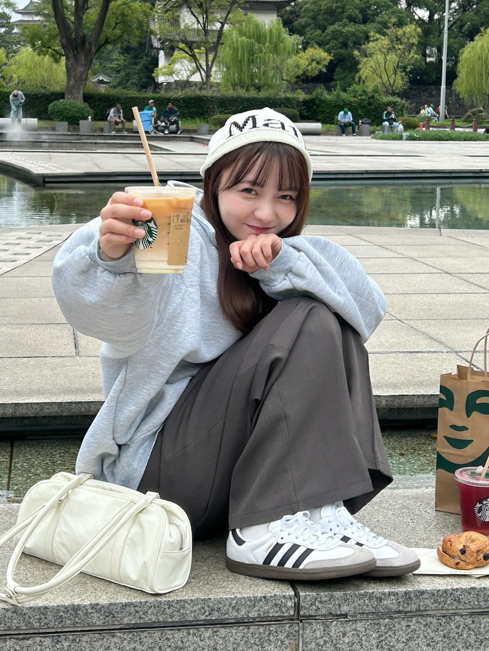 グレー系のスウェット、ホワイト系のバッグ、グレー系のスラックスを着用したレディースの秋コーディネートの2枚目の写真