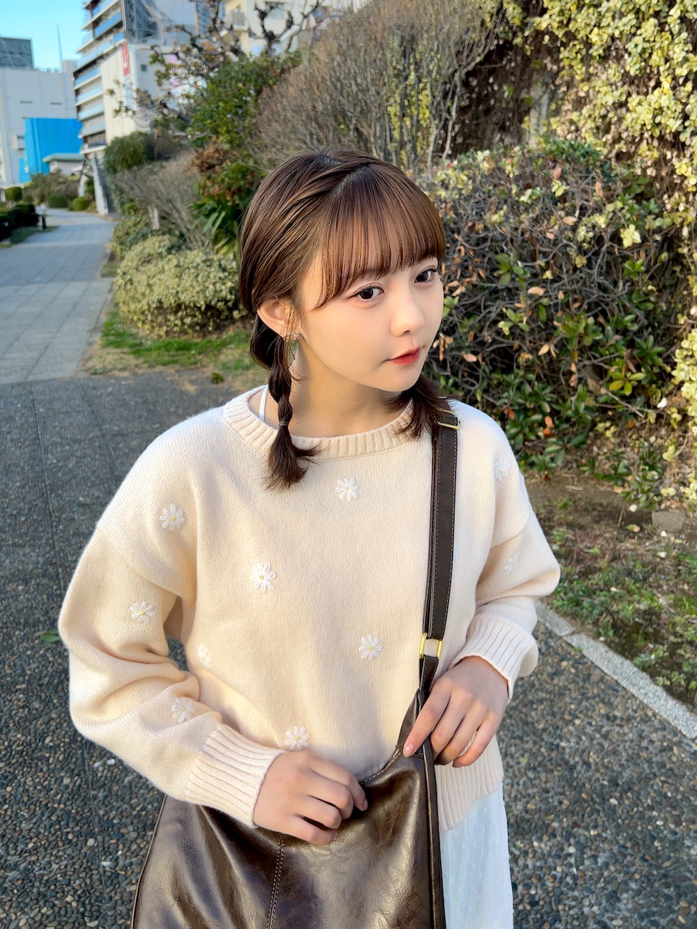 ピンク系のニット/セーター、ブラウン系のショルダーバッグ、ホワイト系のスカートを着用したレディースの冬コーディネートの4枚目の写真