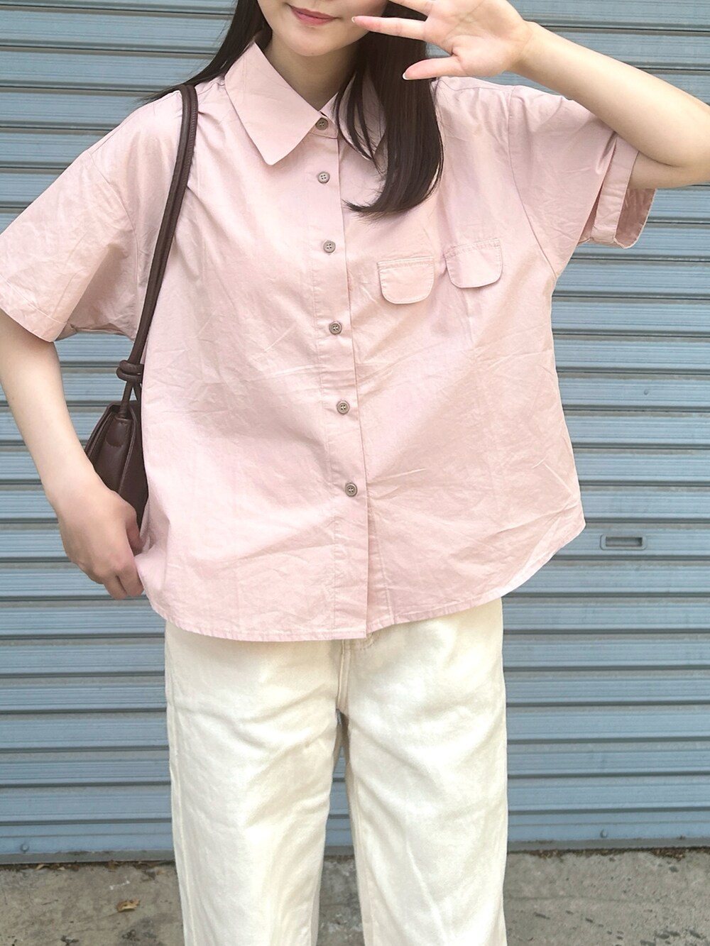 ピンク系のシャツ/ブラウス、ブラウン系のハンドバッグ、ホワイト系のパンツを着用したレディースの夏コーディネートの5枚目の写真