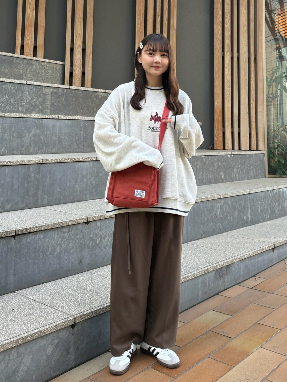 ホワイト系のナイロンジャケット、ベージュ系のスウェット、レッド系のショルダーバッグを着用したレディースの冬コーディネートの3枚目の写真