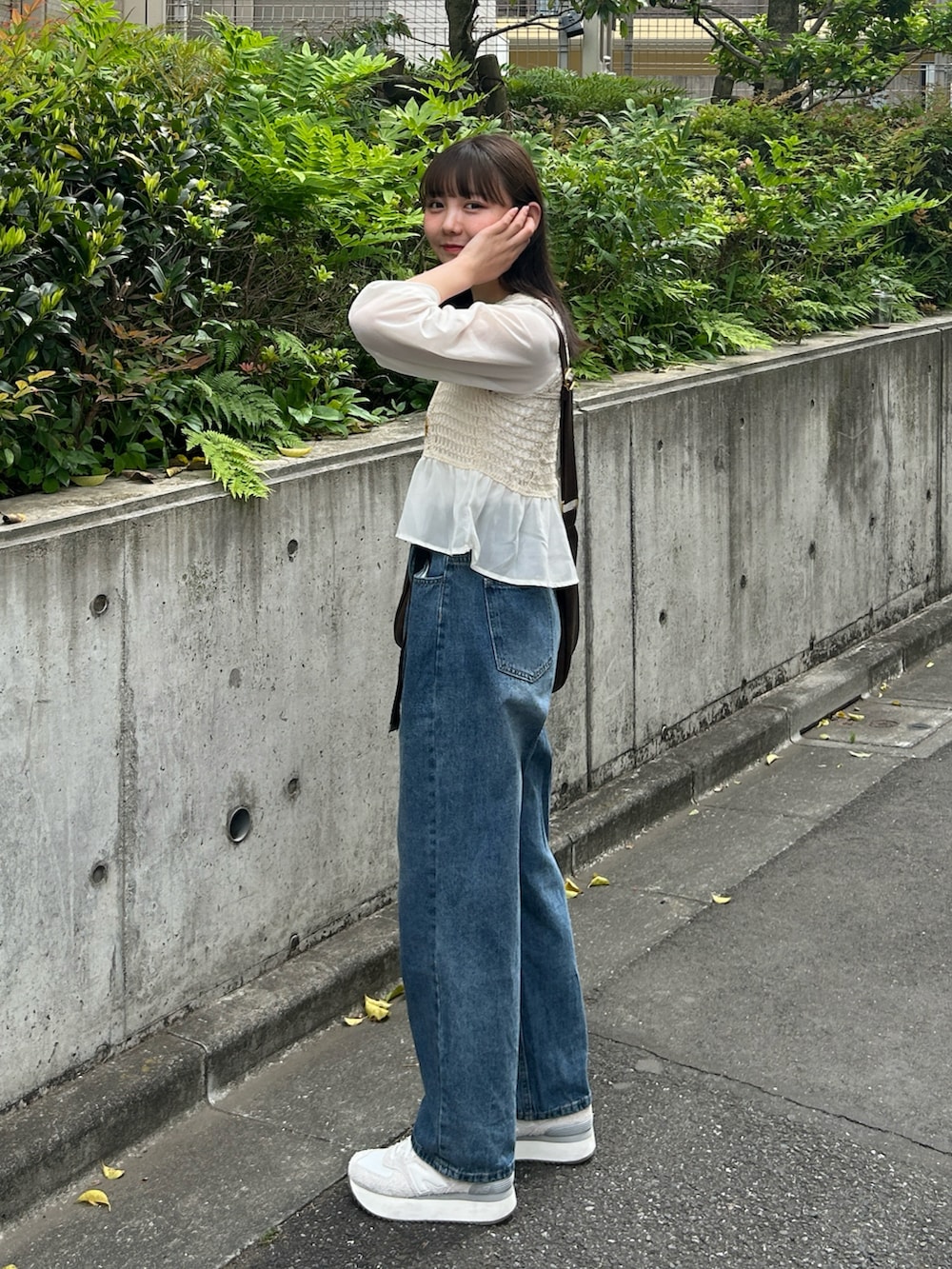 ブルー系のデニムパンツ、ベージュ系のシャツ/ブラウス、ブラウン系のショルダーバッグを着用したレディースの春コーディネートの4枚目の写真