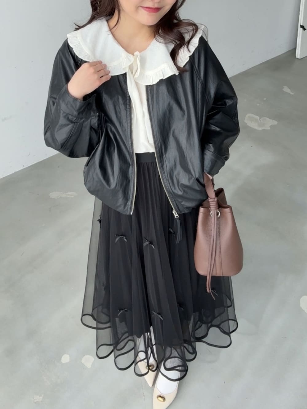 ホワイト系のシャツ/ブラウス、ブラック系のスカート、ブラウン系のハンドバッグを着用したレディースの春コーディネートの2枚目の写真