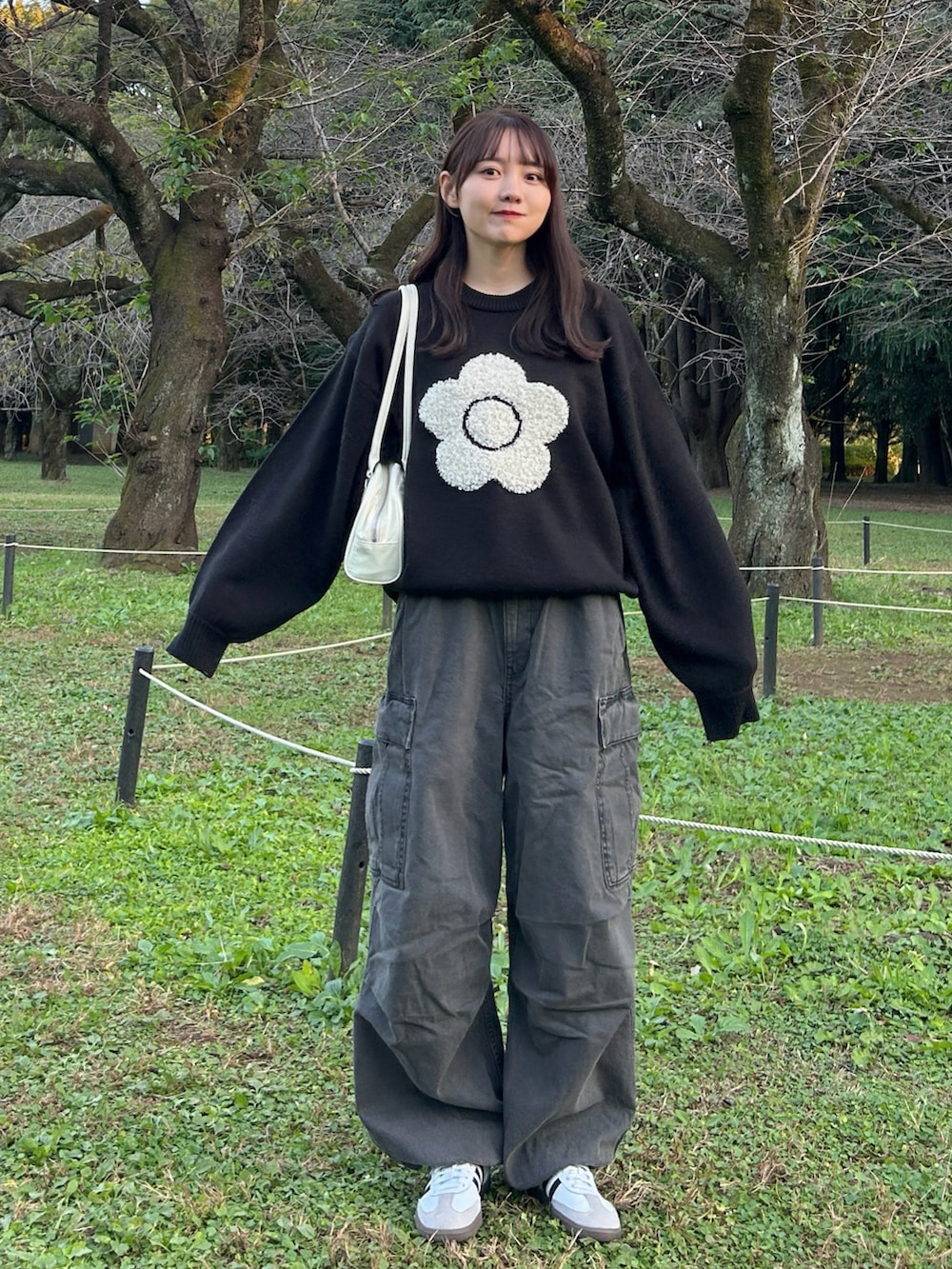 ホワイト系のバッグ、ブラック系のニット/セーター、グレー系のデニムパンツを着用したレディースの冬コーディネートの2枚目の写真